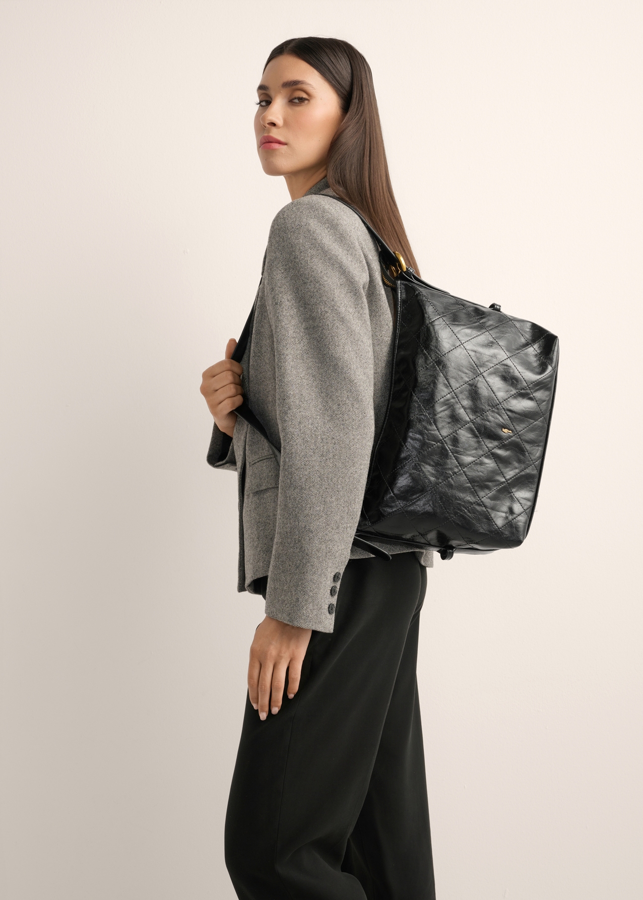 Black women's shoulder bag with stitching TOREC-1248-9P(Z26), product view on model's shoulder. Half of silhouette visible.