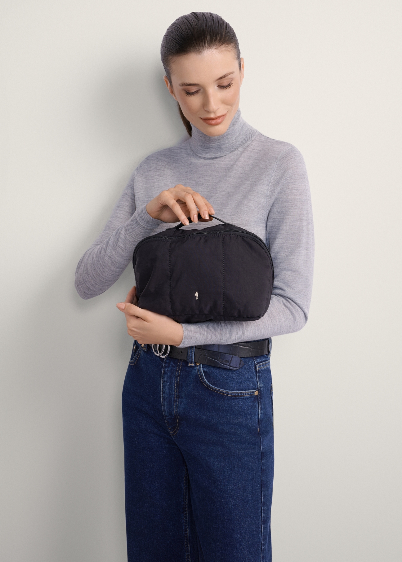 Black women's cosmetic bag TOREN-0323-99(Z25), front view of the product on a model, half of the silhouette visible.