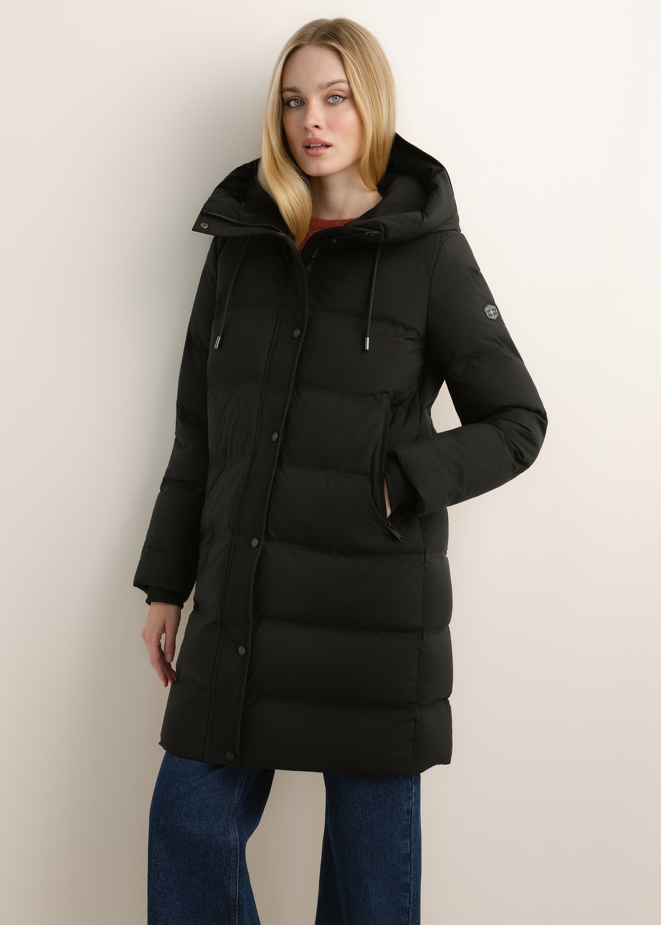 Black women's winter jacket with hood KURDT-0700-99(Z26), front view of the product on the model. Half of the silhouette visible.