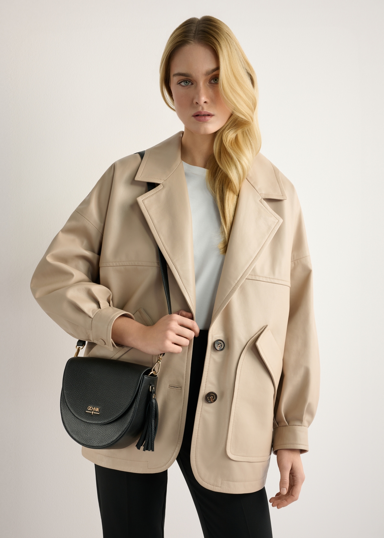 Women's black leather messenger bag TORES-1283-9I(W26) - front view of the product, on a model, against a light background. Half-length silhouette visible.