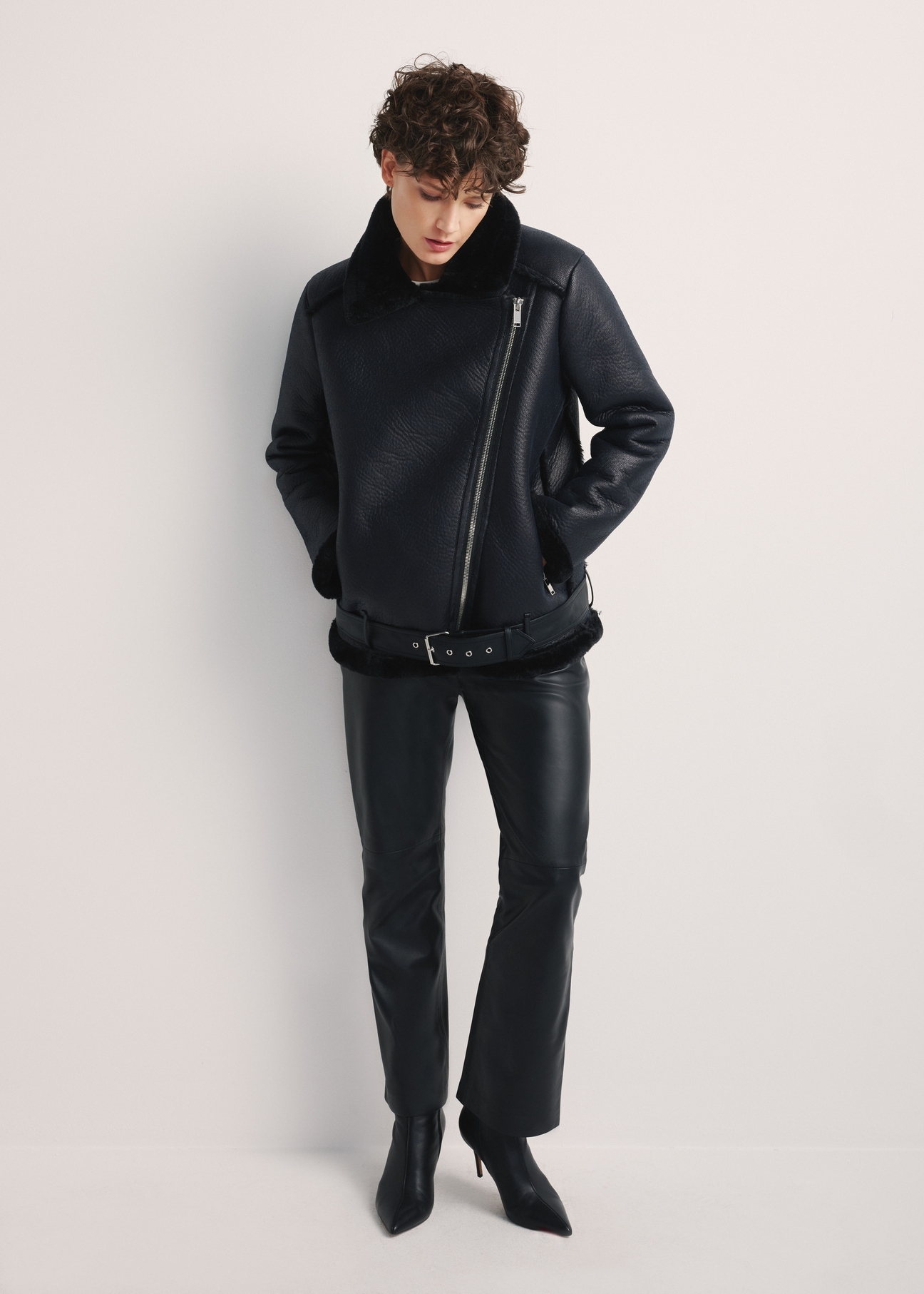 Black short women's sheepskin coat KOZDP-0001A-99(Z24), front view of the product on the model, the entire silhouette is visible.
