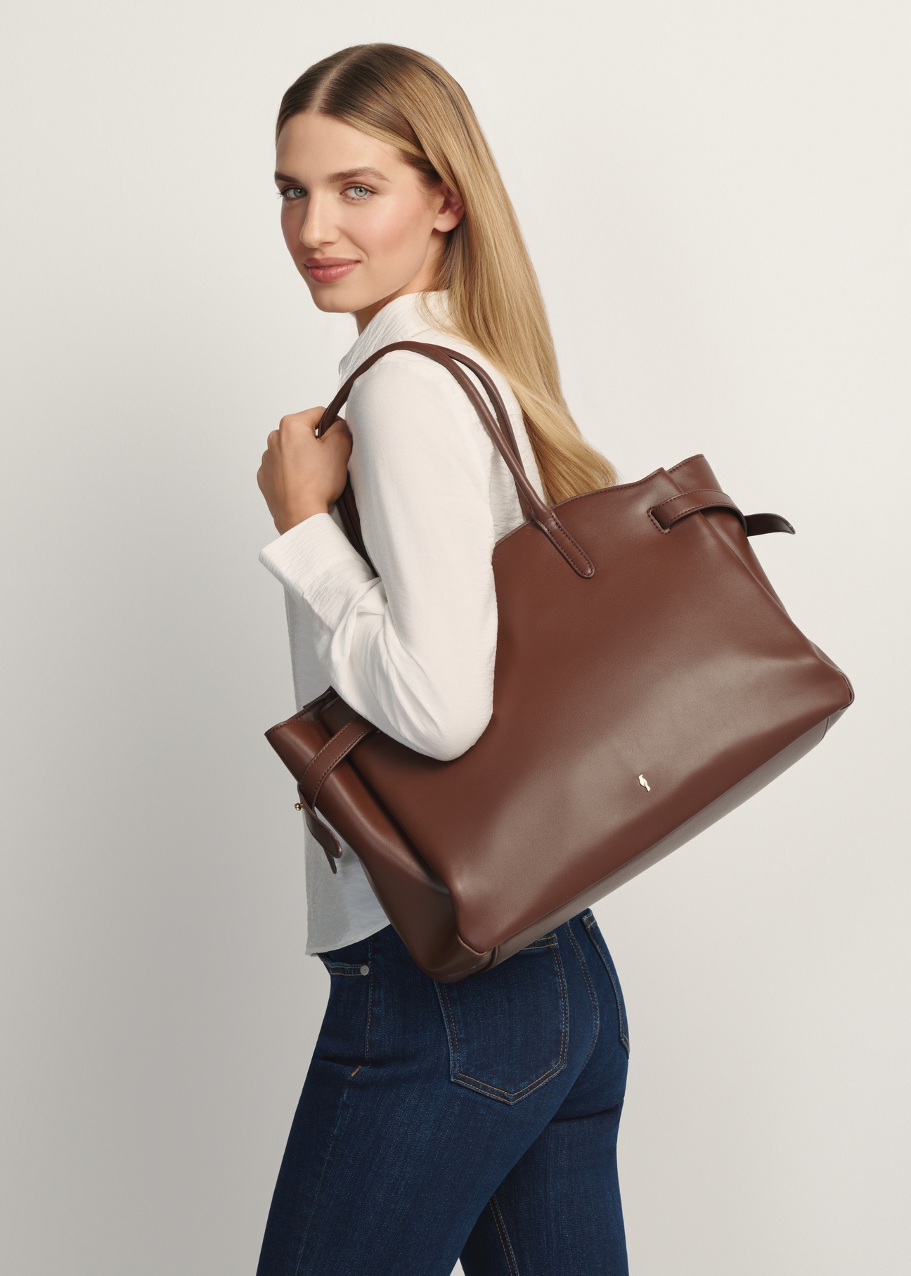 Large brown women's handbag TOREC-1135-1H(W26) - front view of the product, with the model standing sideways against a light background. Half of the silhouette visible.
