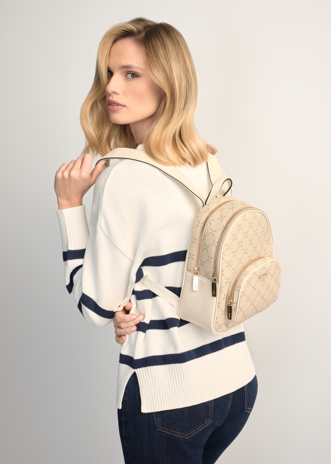 Cream women's backpack with monogram TOREC-1026-0P(W26), product view on model's back. Half of silhouette visible.