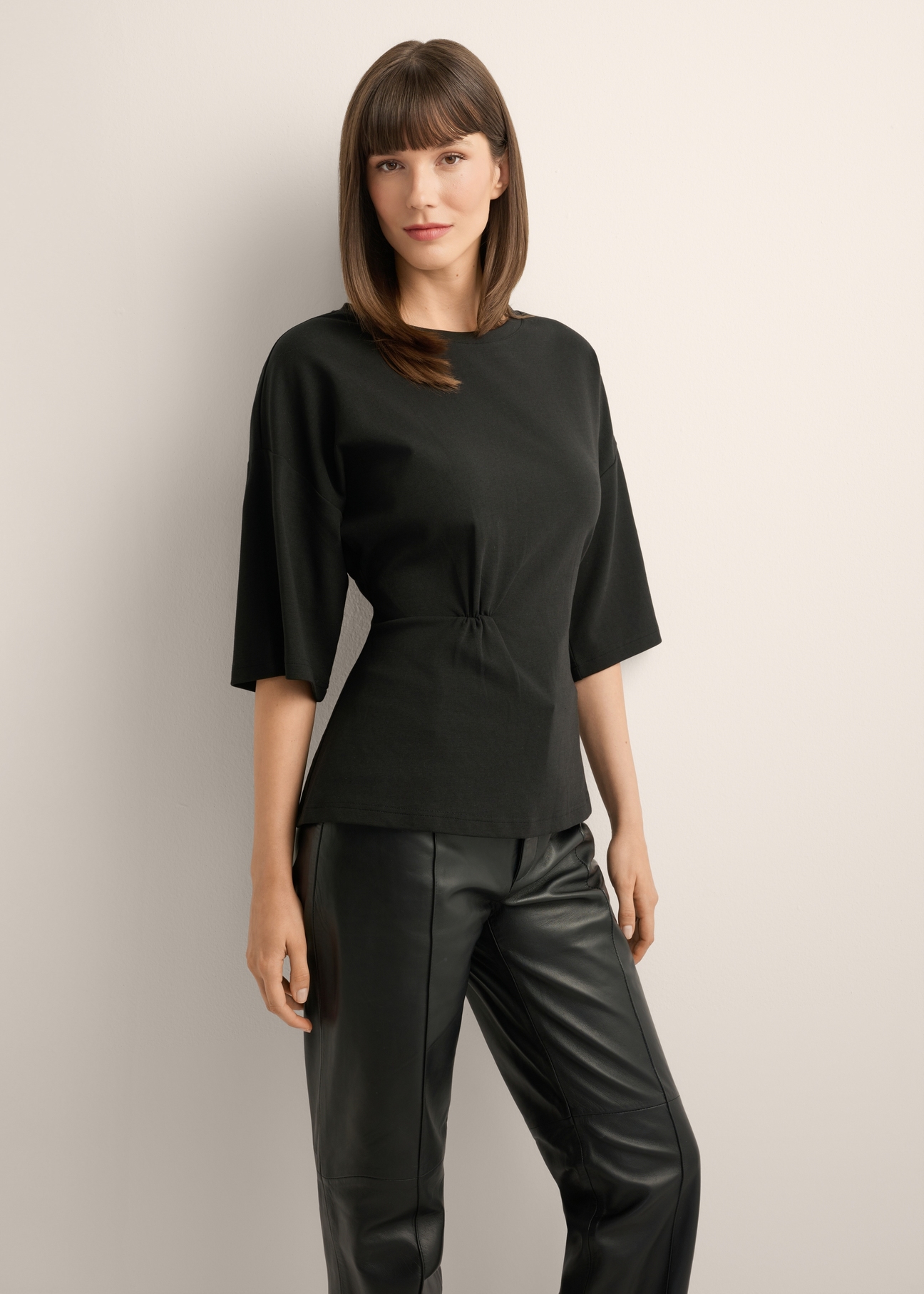 Black women's blouse with draping TSHDT-0163-99(Z26), front view of the product on the model, half of the silhouette visible.