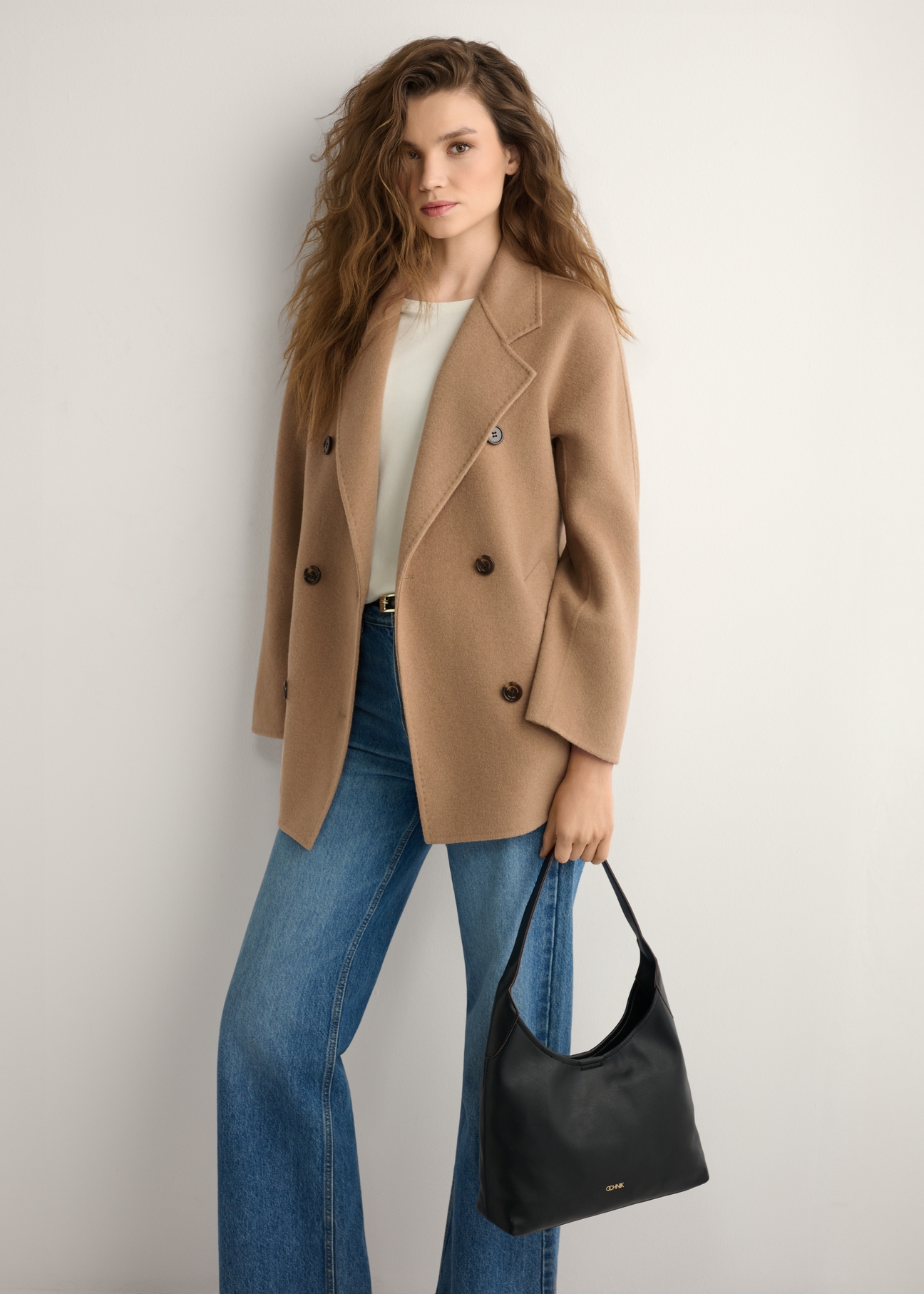 Black medium women's handbag TOREC-1200-99(W26), product view in model's hand. Half of silhouette visible.