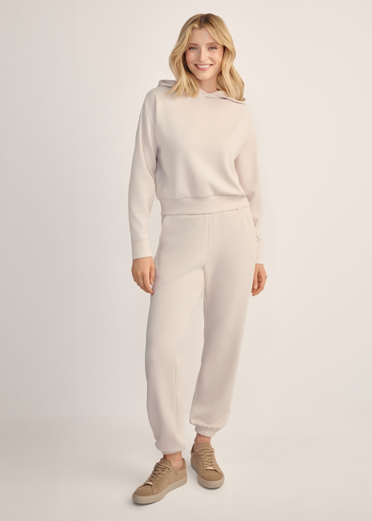 Light beige women's hooded sweatshirt BLZDT-0118-1A(Z26), front view of the product on the model. Full body visible.