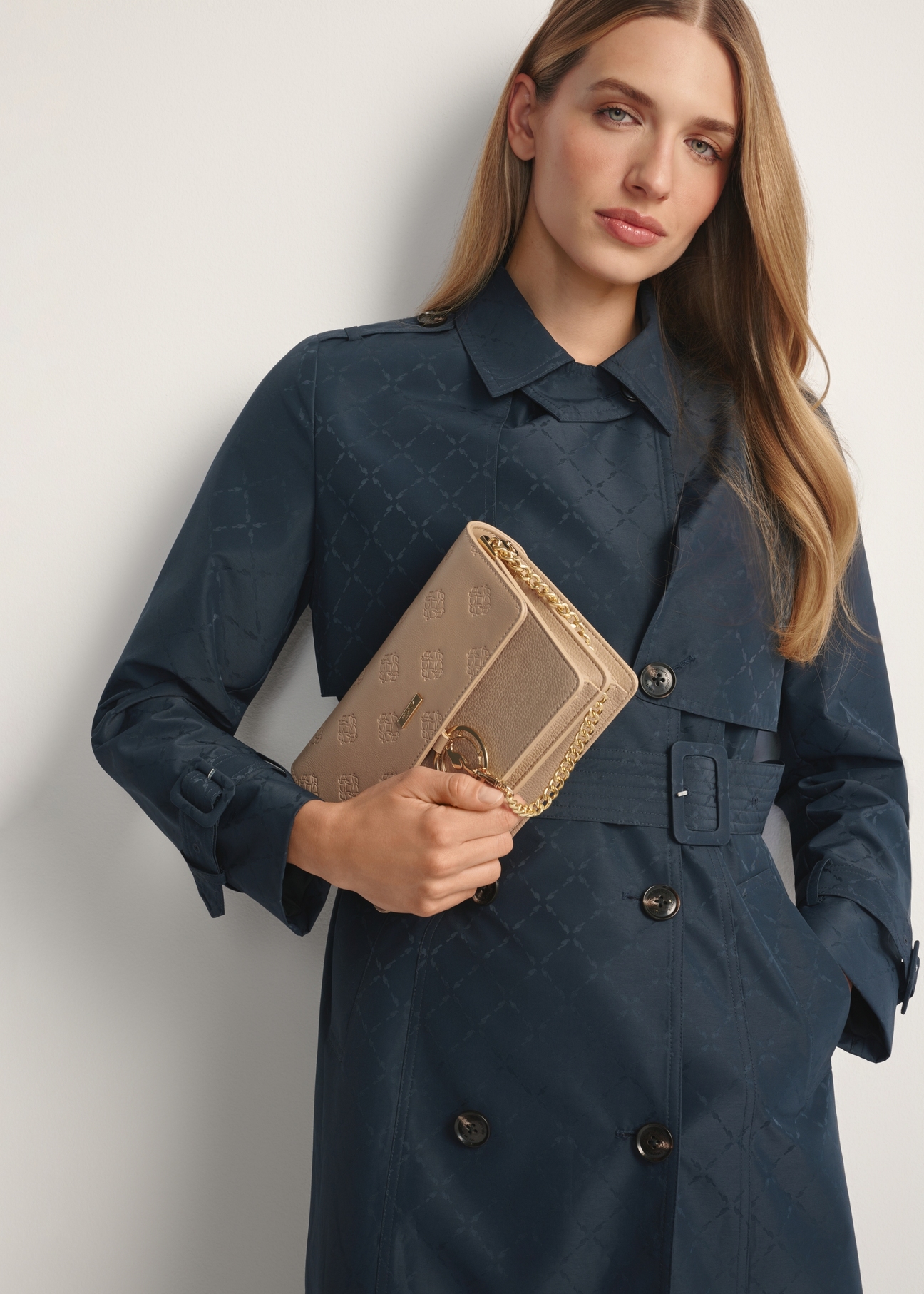 Beige women's monogram handbag TOREC-0536-1P(W26), product view in model's hand. Half of silhouette visible.