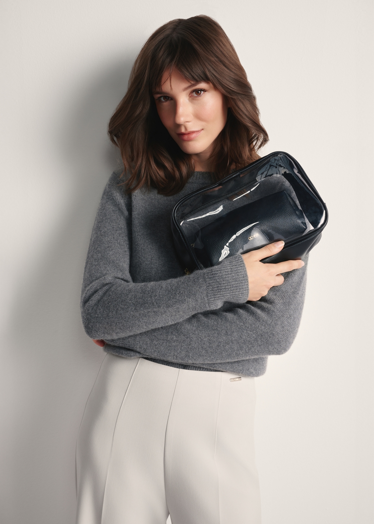 Large two-piece women's cosmetic bag TOREC-0874A-99(Z25), view of the product in the model's hands. Half of the figure visible.