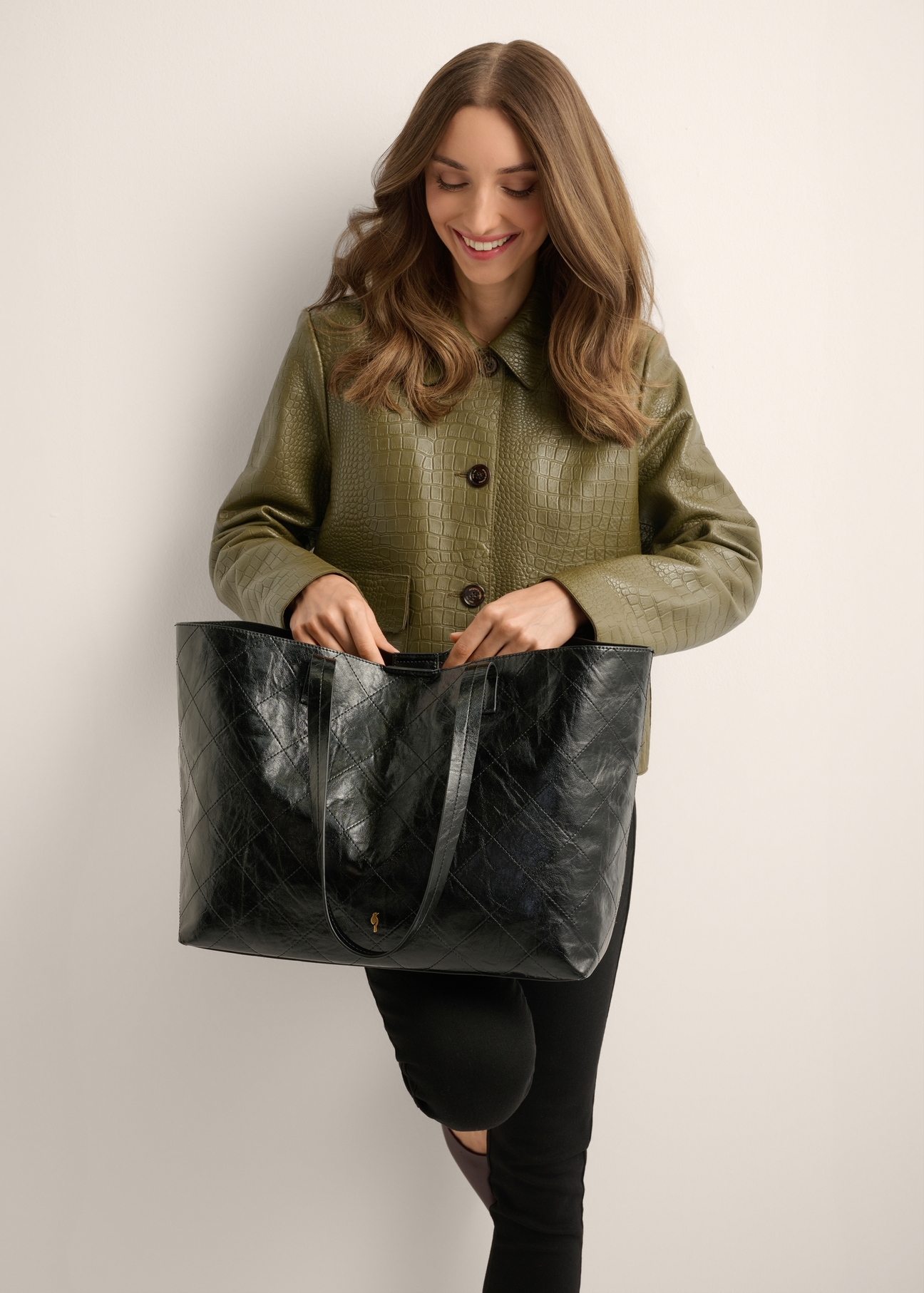 Black women's shopper bag with stitching TOREC-1247-9P(Z26), product view on the model's silhouette, on a light background.