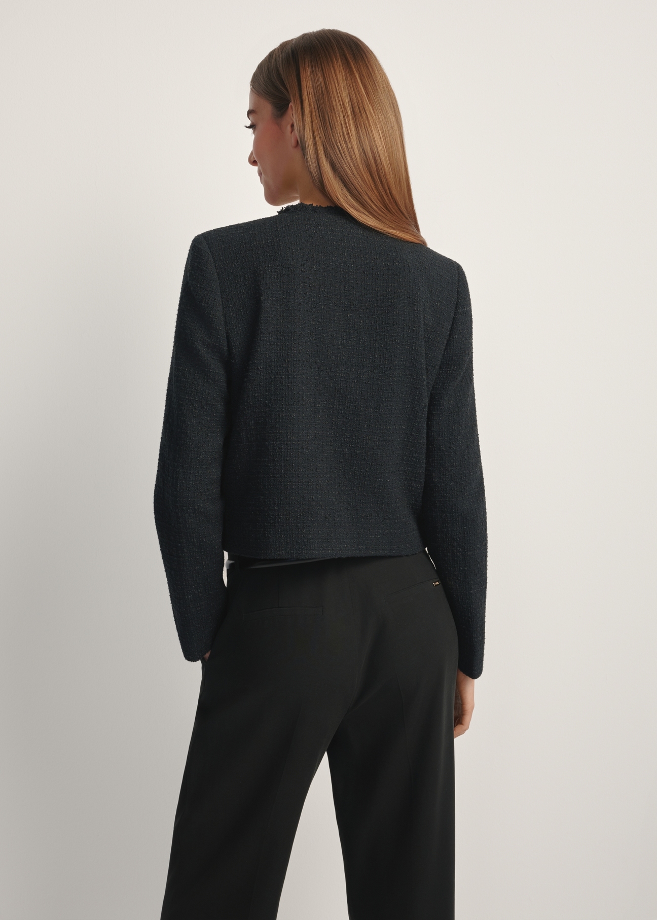 Women's black short blazer ZAKDT-0041-99(W26), back view of the product on the model. Half of the silhouette visible.