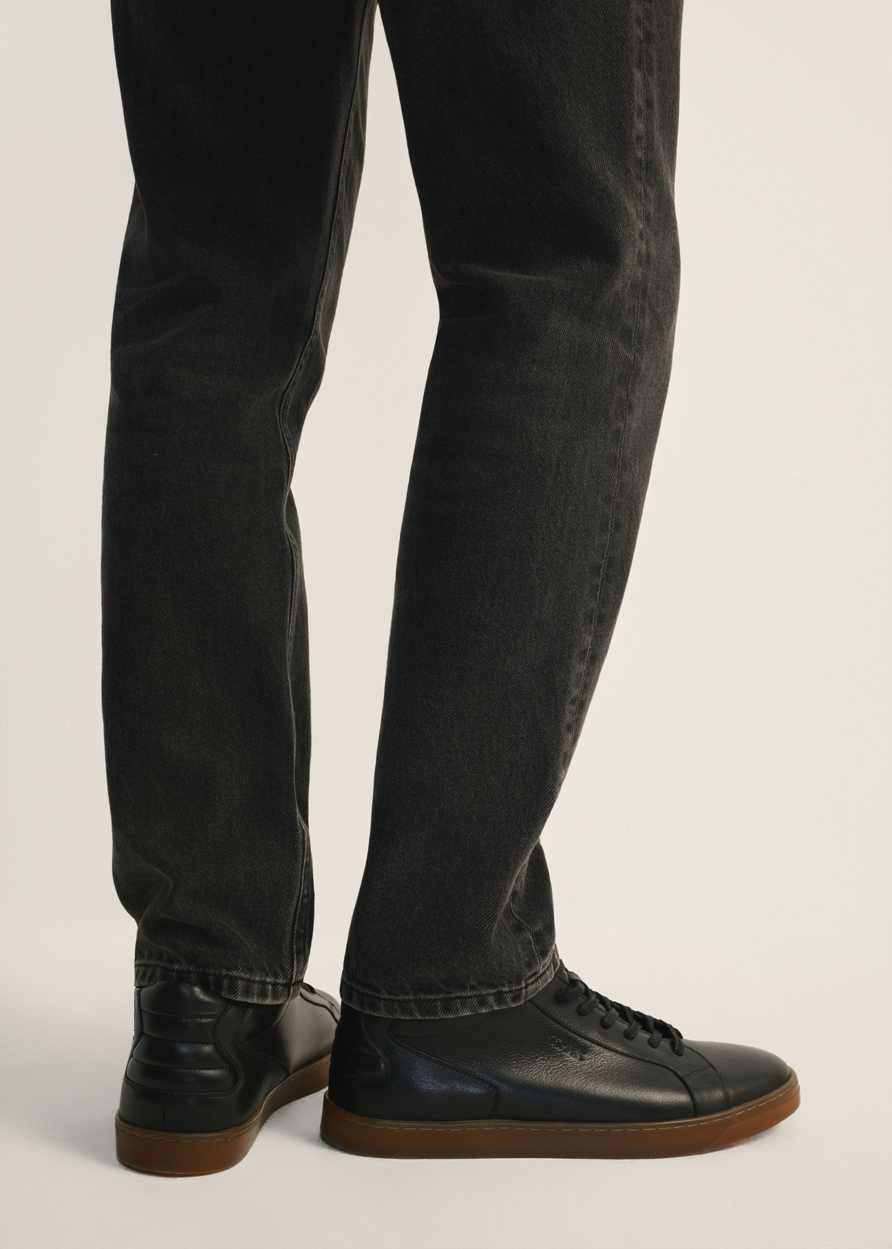 Black men's leather sneakers BUTYM-0405C-99(Z26), side view of the product on the model, half of the silhouette visible.
