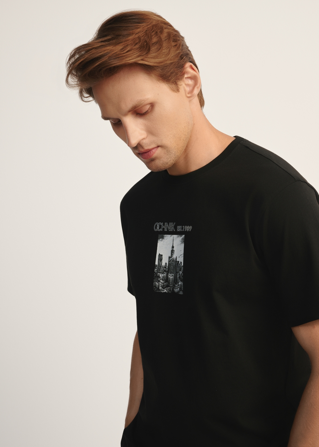 Black men's T-shirt with print TSHMT-0132-99(Z25), diagonal view of the product on the model, half of the silhouette visible.