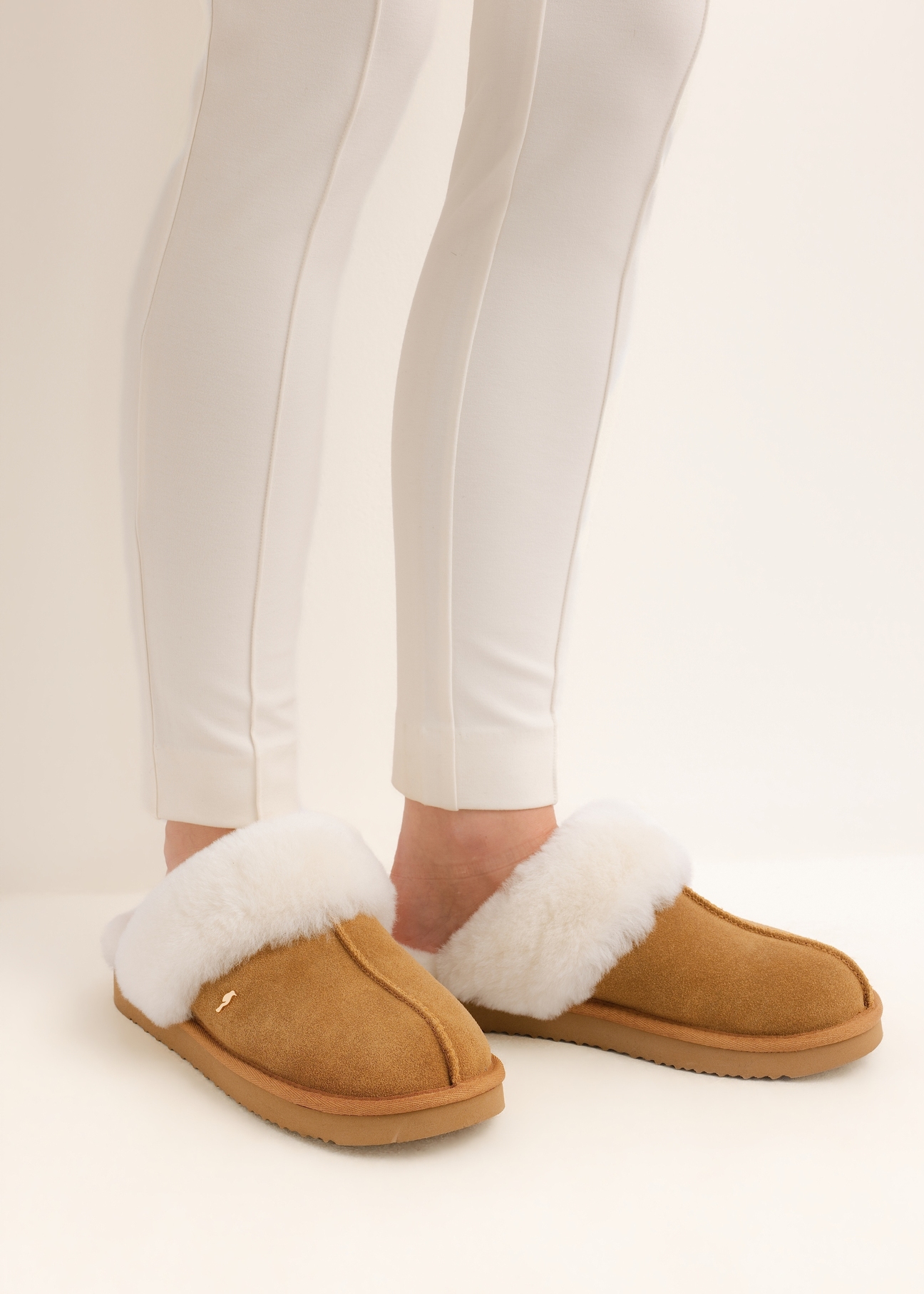 Beige slip-on slippers in a snow-boot style (BUTYD-1137-1F(Z26)), side view of the product on a model's feet, against a light background.