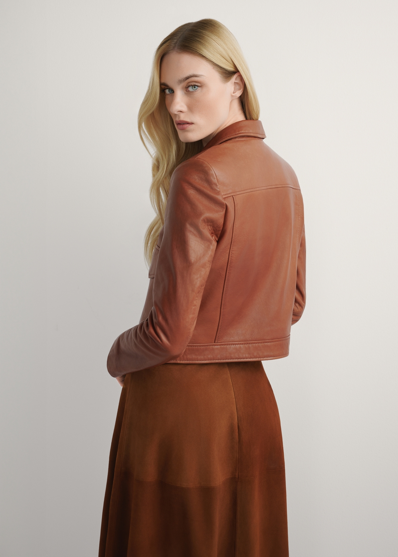 Women's short leather jacket in camel color KURDS-0471-1D(W26), back view of the product on the model. Half of the silhouette visible.