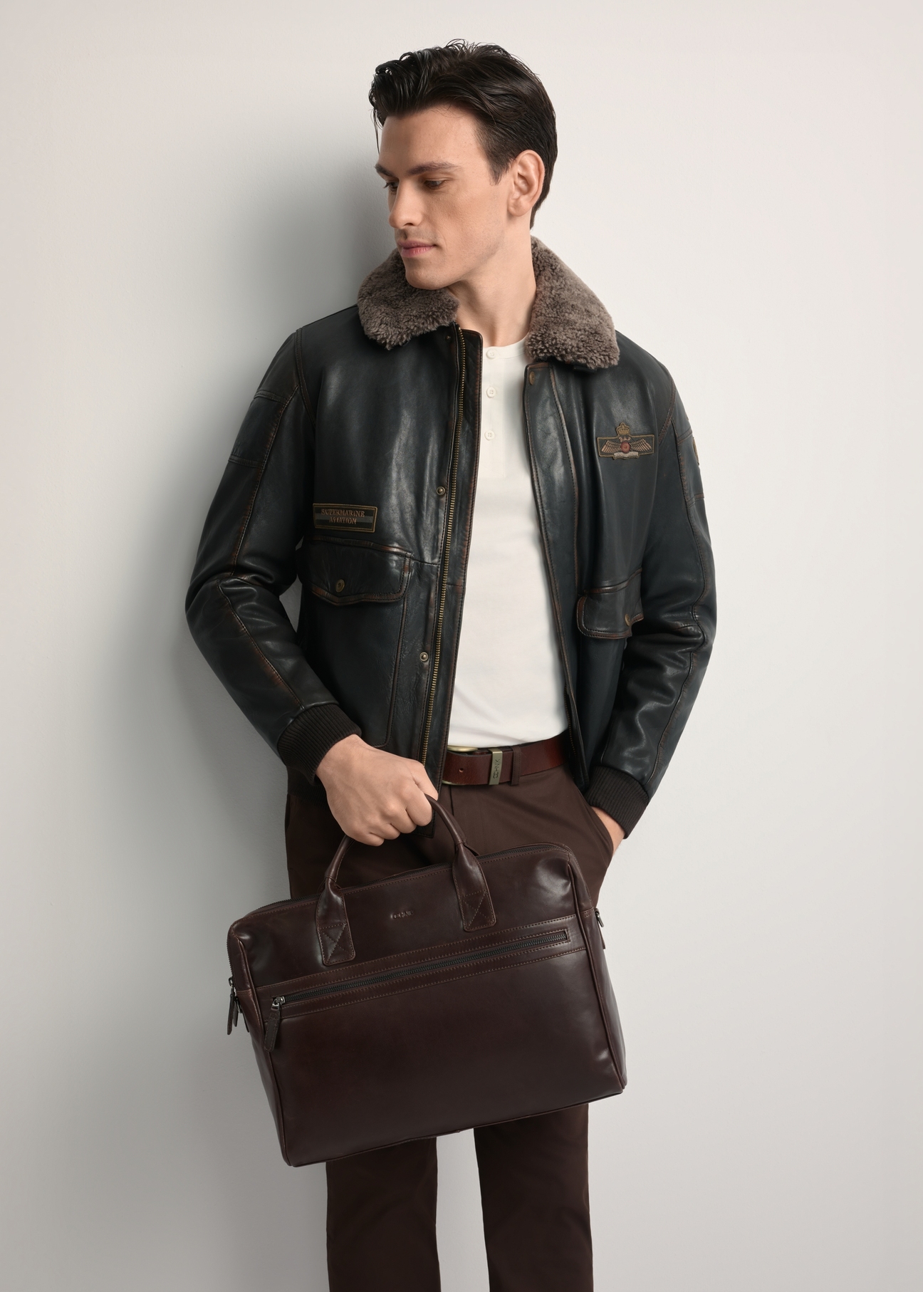 Brown leather men's bag TORMS-0460-89(Z25) - front view of the product, held by the model. Half of the silhouette visible.