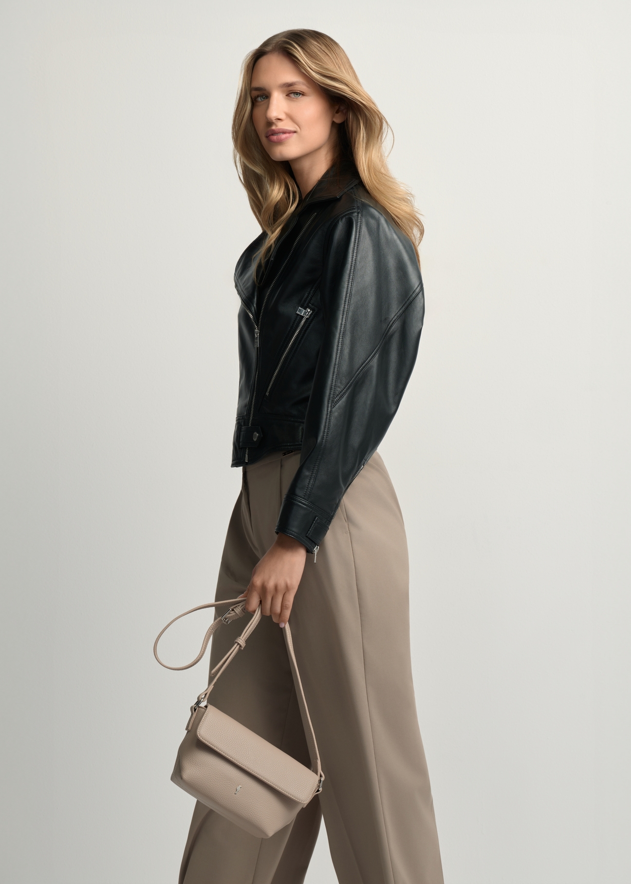 Beige small women's shoulder bag TOREC-0916-1A(W26) - front view of the product, held by the model, against a light background. Knee-length silhouette visible.