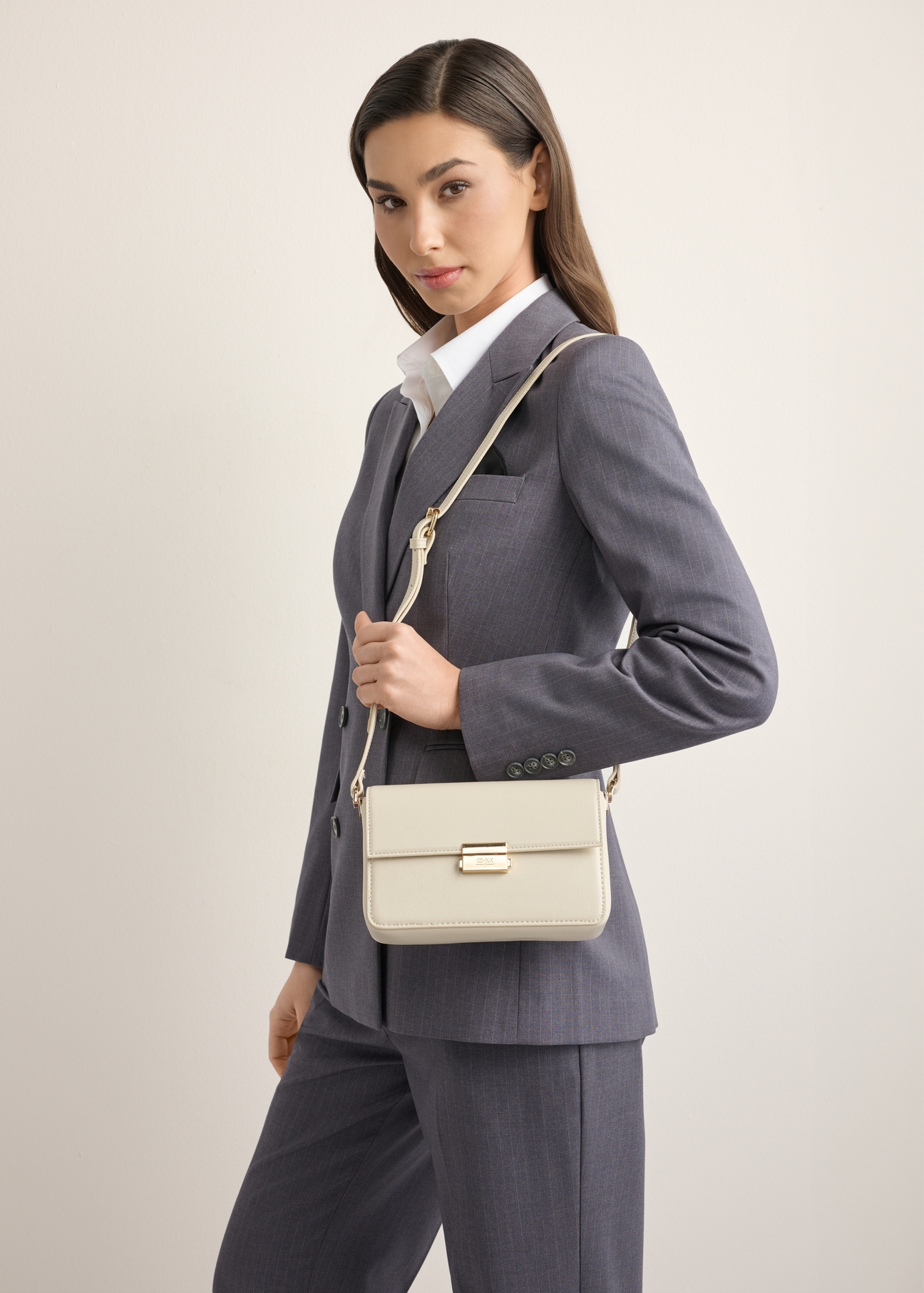Elegant cream women's handbag TOREC-1251-0B(Z26), front view of the product on a model. Half of the silhouette visible.