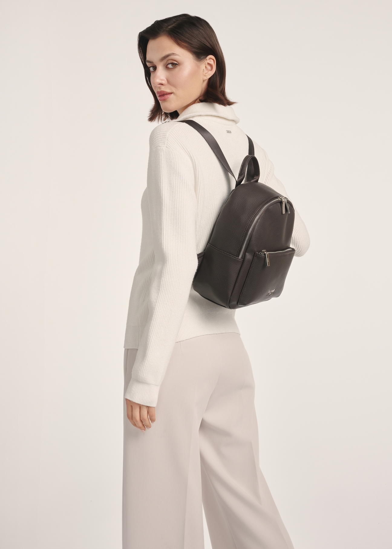 Dark brown women's backpack TOREC-0996A-89(Z25), front view of the product on a model, half of the silhouette visible.