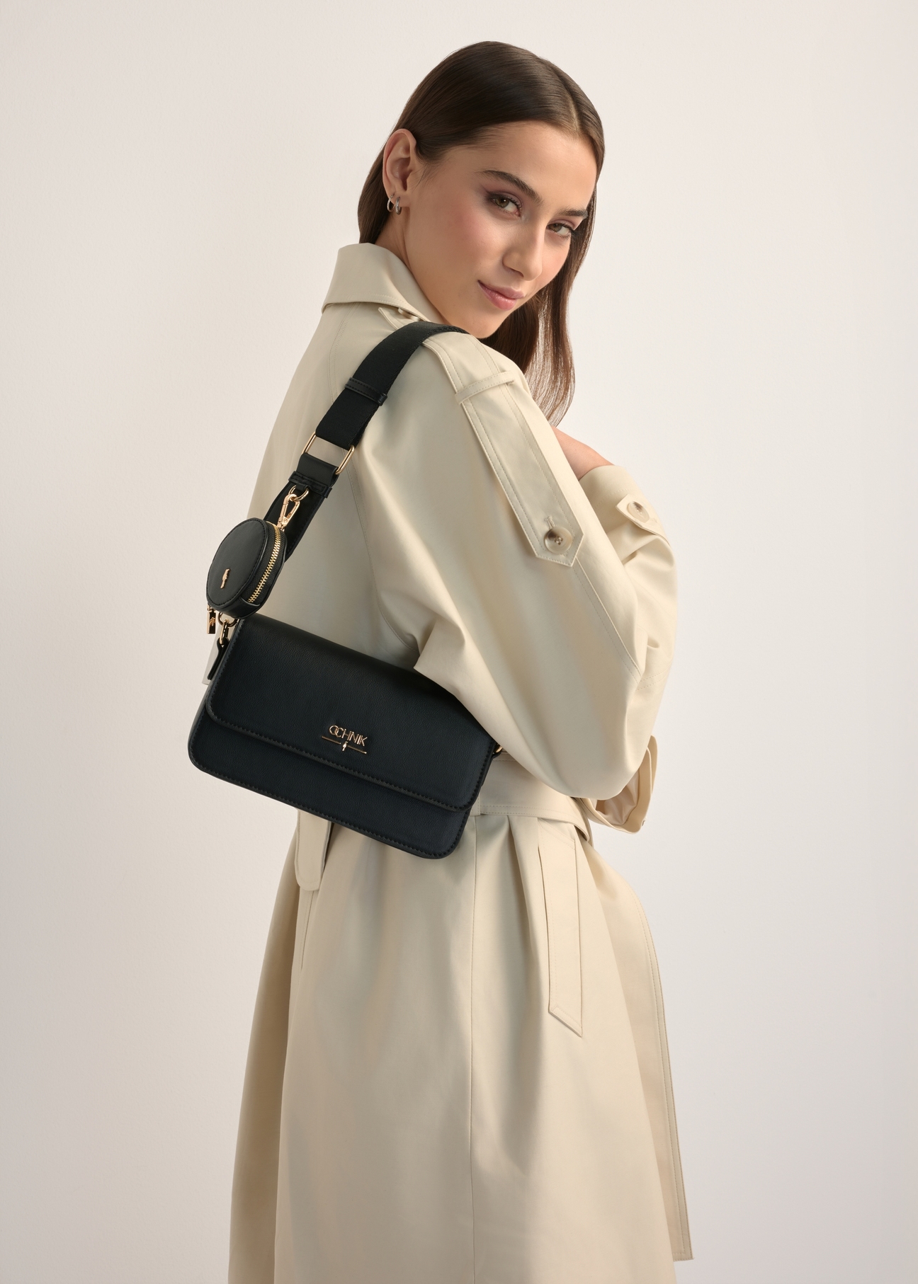 Small black women's handbag TOREC-1171-99(W26), product view on model's shoulder. Half of silhouette visible.