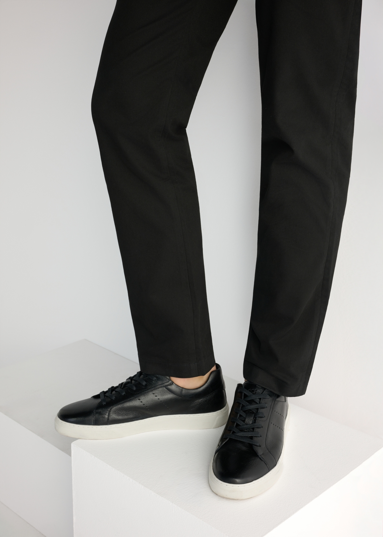 Black men's leather sneakers BUTYM-0486-99(W26), side view of the product on the model, half of the silhouette visible.