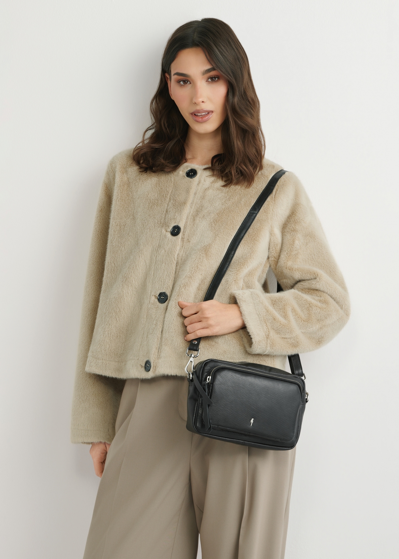 Small black leather women's handbag TORES-1023A-99(W26), front view of the product on the model's shoulder. Half of the silhouette visible.