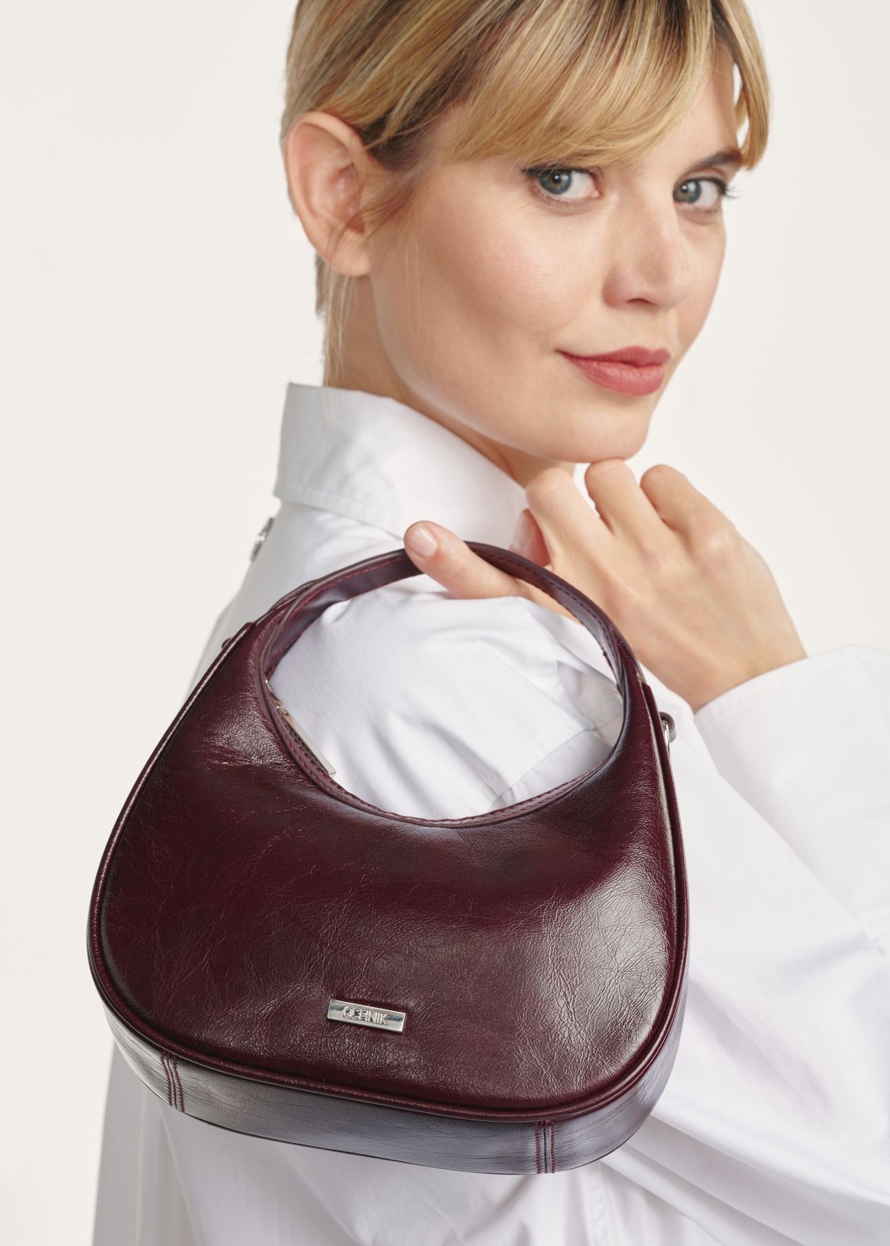 Small burgundy leather hobo bag TORES-1174-49(Z25), close-up on model on white background.