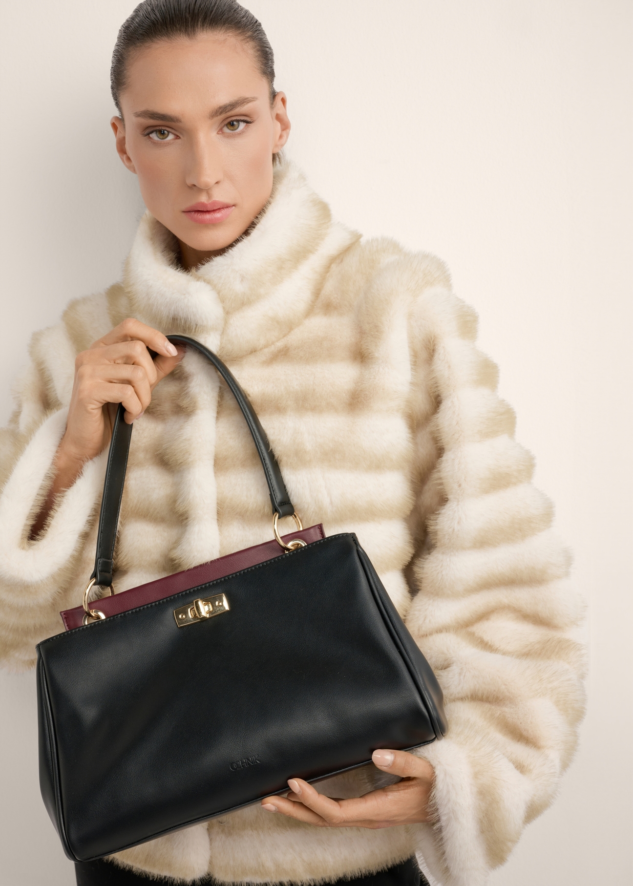 Black women's shoulder bag TOREC-1376-99(Z26), view of the product in the model's hands, on a light background.