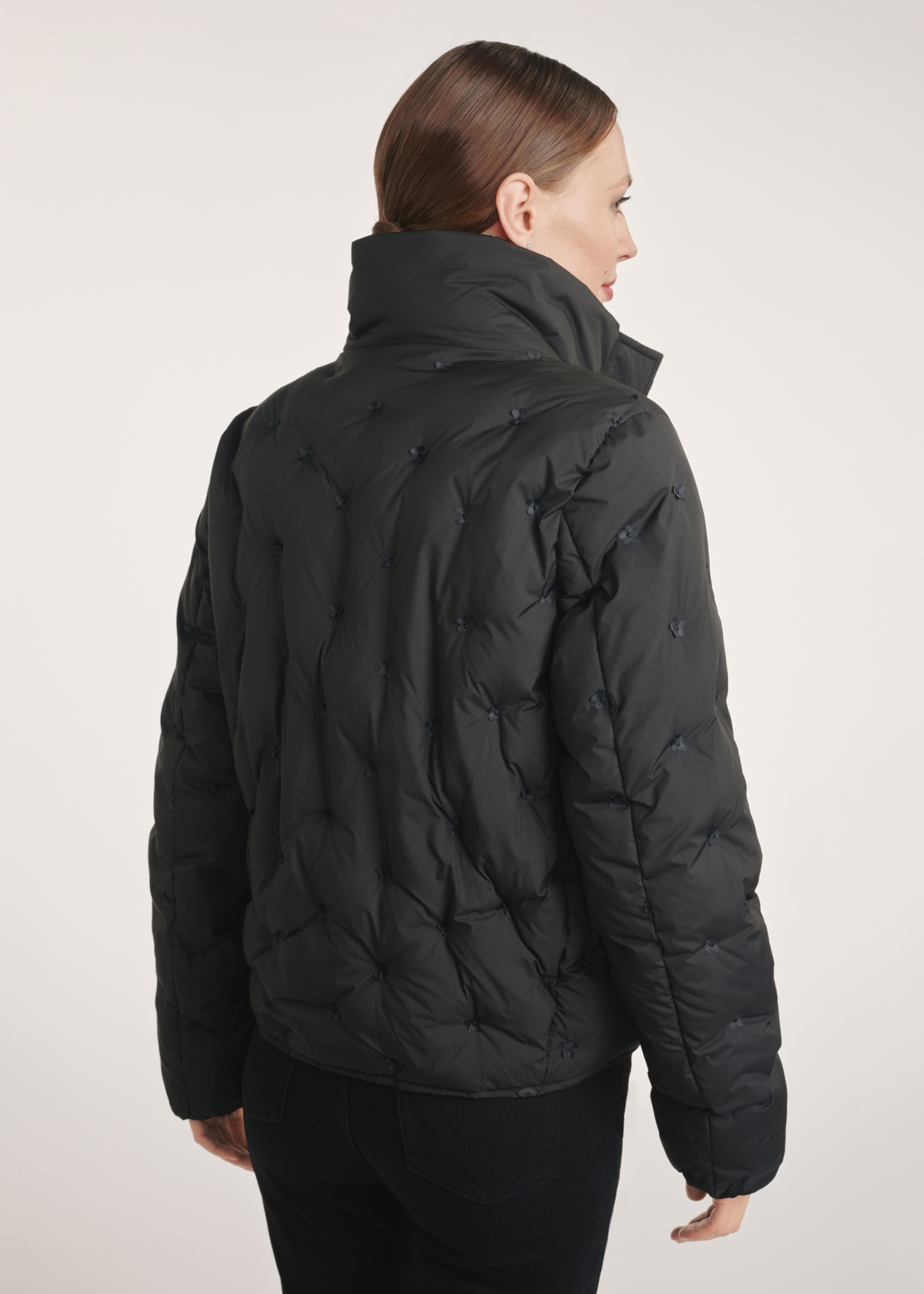 Black women's winter jacket KURDT-0614-99(Z25), product view from the back on the model, half of the silhouette visible.