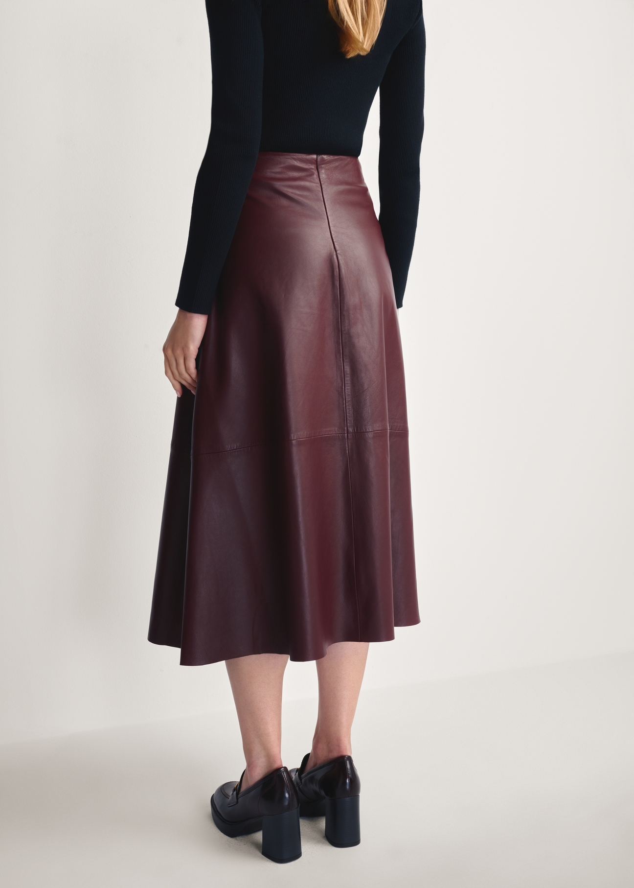 Burgundy leather midi skirt SPCDS-0077-2869(Z25), product view from the back on the model. Half of the silhouette visible.