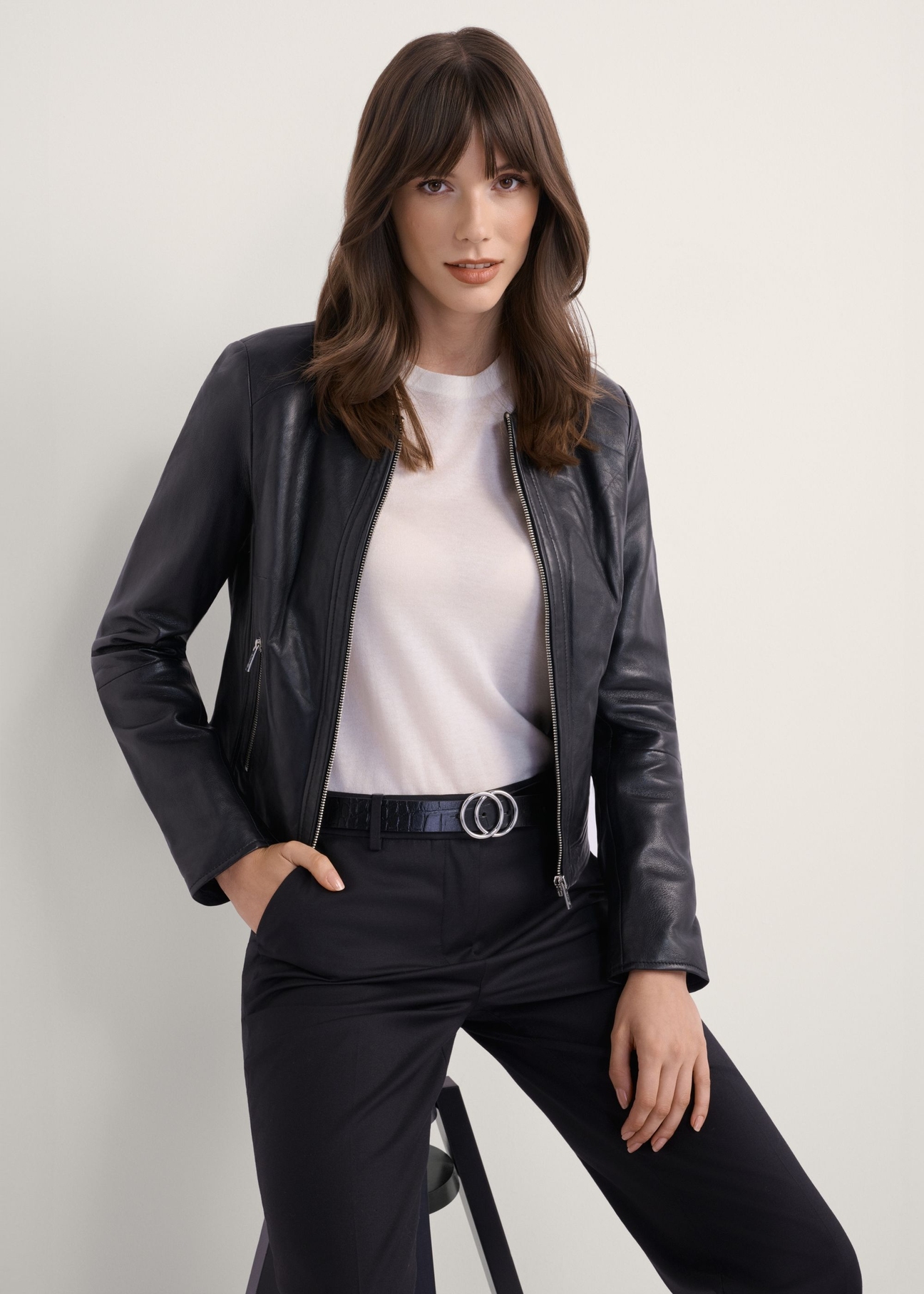 Women's black short leather jacket KURDS-0294-99(KS), front view of the product on the model. Half of the silhouette visible.