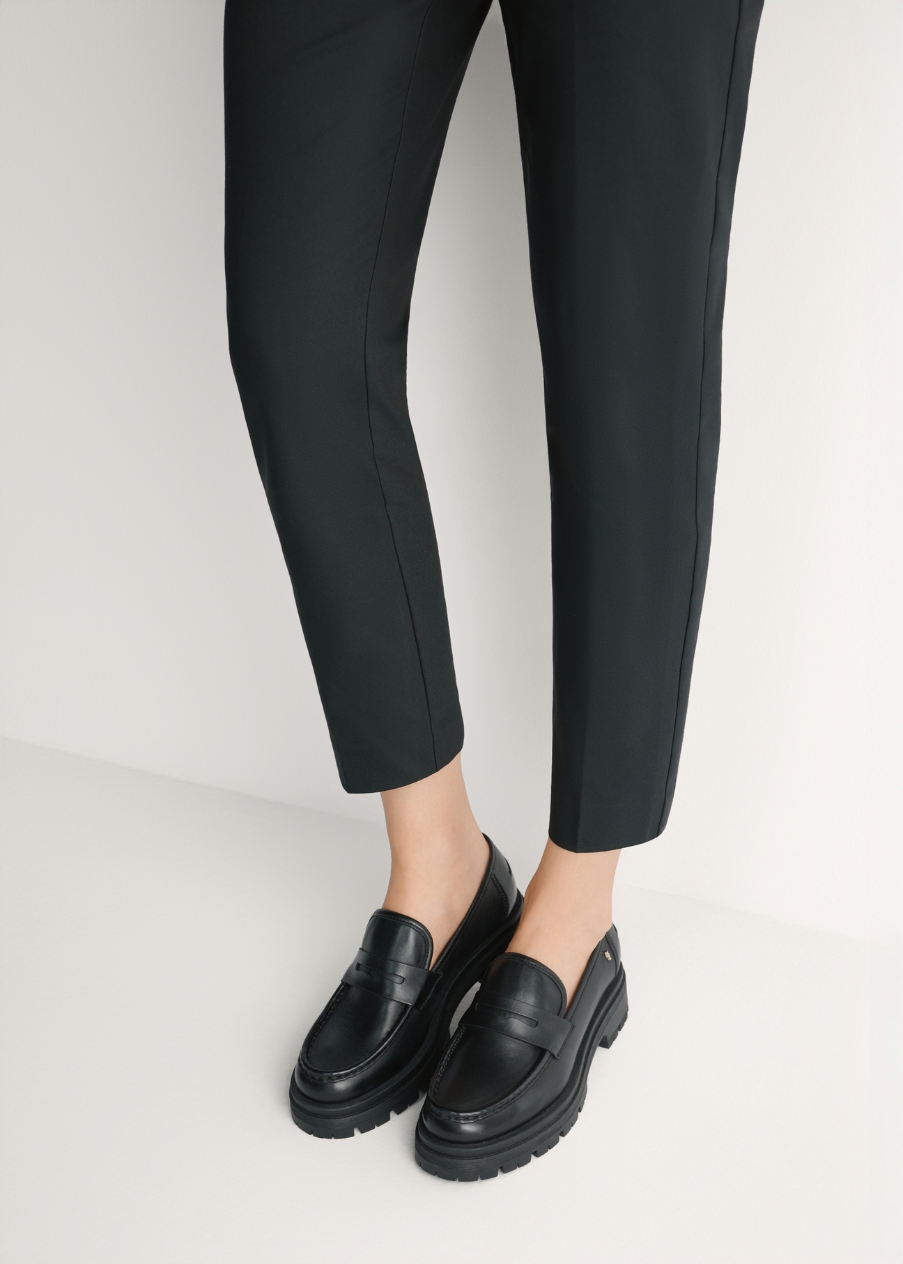 Women's black leather loafers BUTYD-1069-99(W26) - front view of the product, on a model, against a light background. Knee-length silhouette visible.