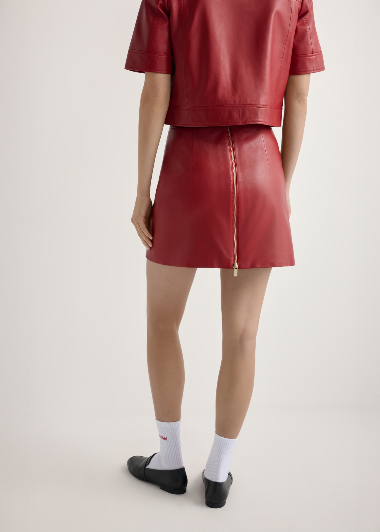 Red women's leather mini skirt SPCDS-0081-4B(W26), product view from the back on the model, half of the silhouette visible.
