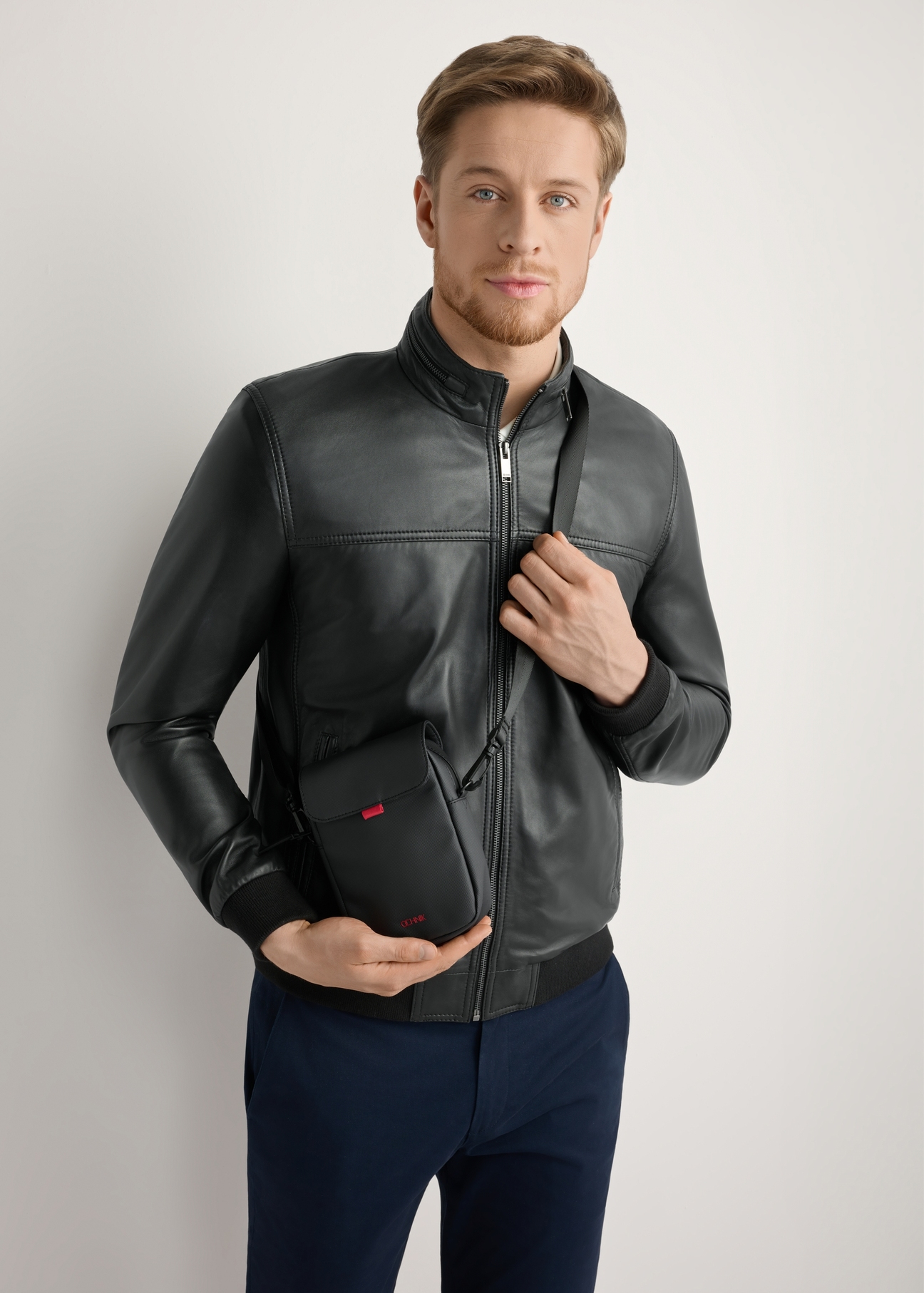 Men's small black messenger bag TORMN-0399-9J(W26), product view on the model's silhouette, on a light background.