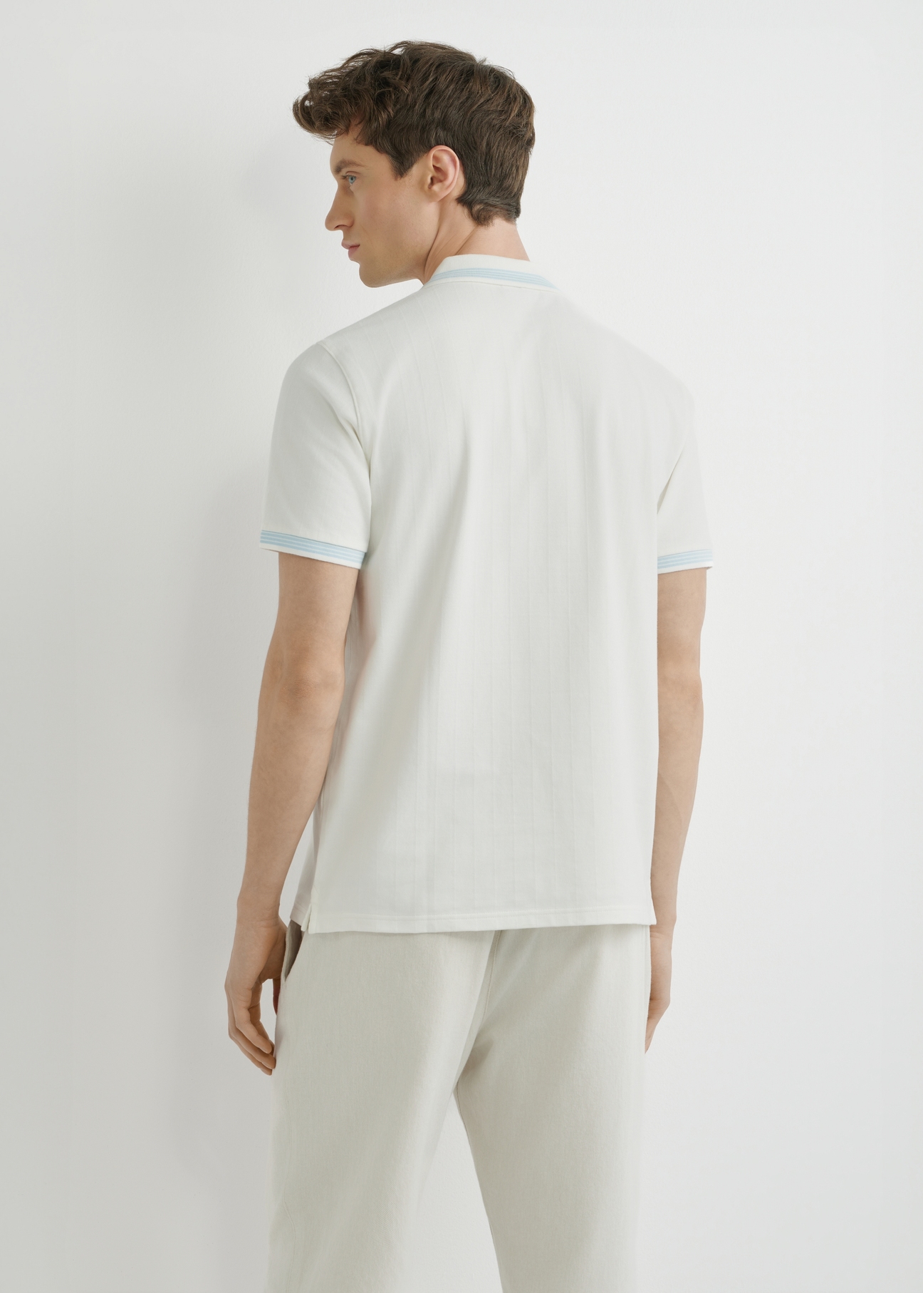 White polo shirt POLMT-0090-0B(W26), back view of the product on the model. Half of the silhouette visible.