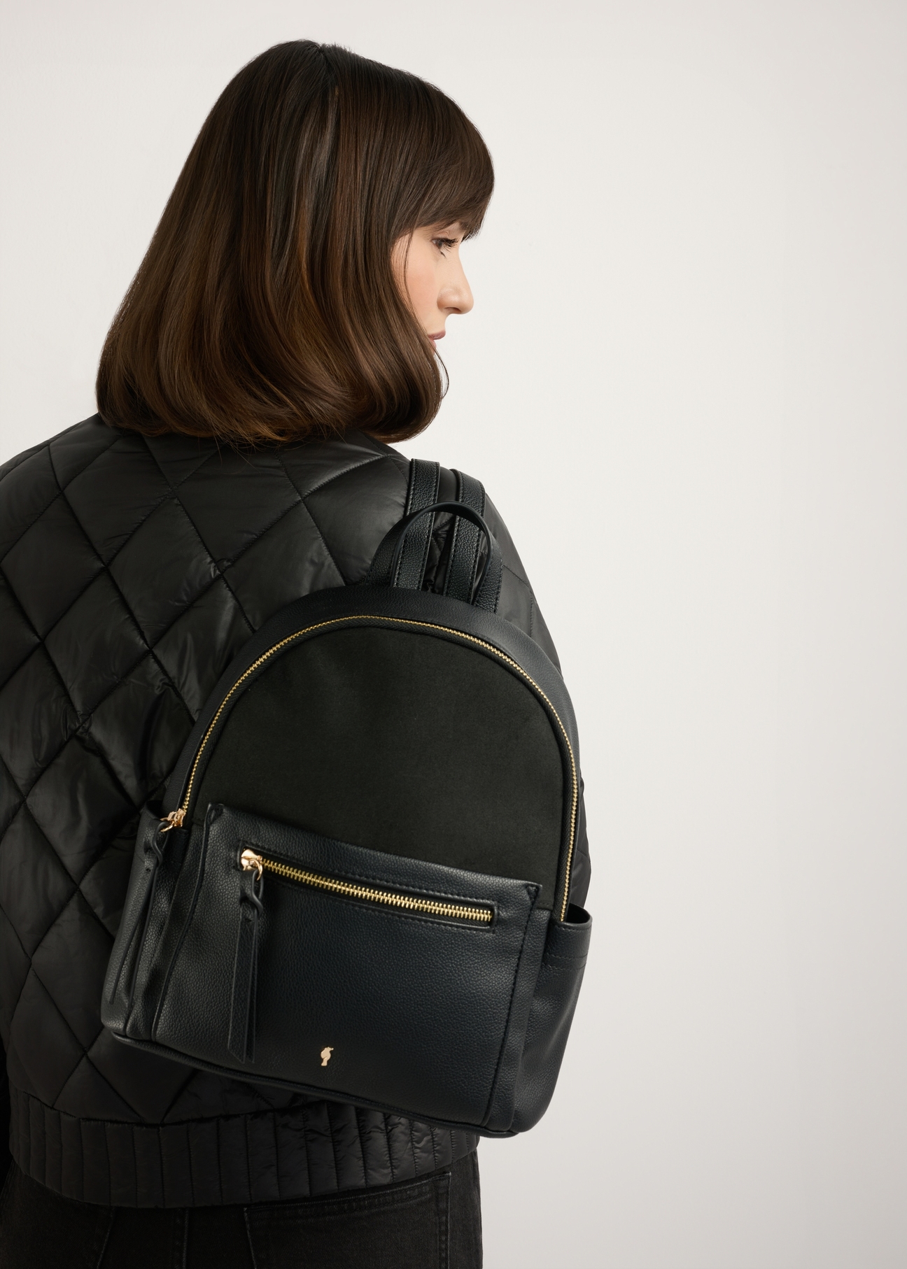 Black women's backpack TOREC-1125-99(W26), product view on model's back. Half of silhouette visible.