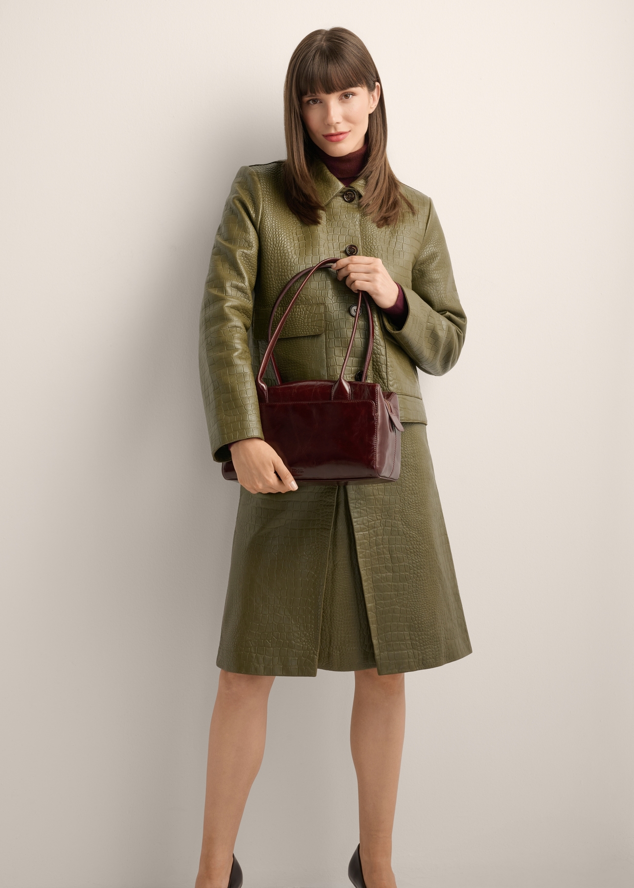 Women's burgundy leather shoulder bag TORES-1392-4E(Z26) - front view of the product, held by the model, against a light background. The entire silhouette is visible.