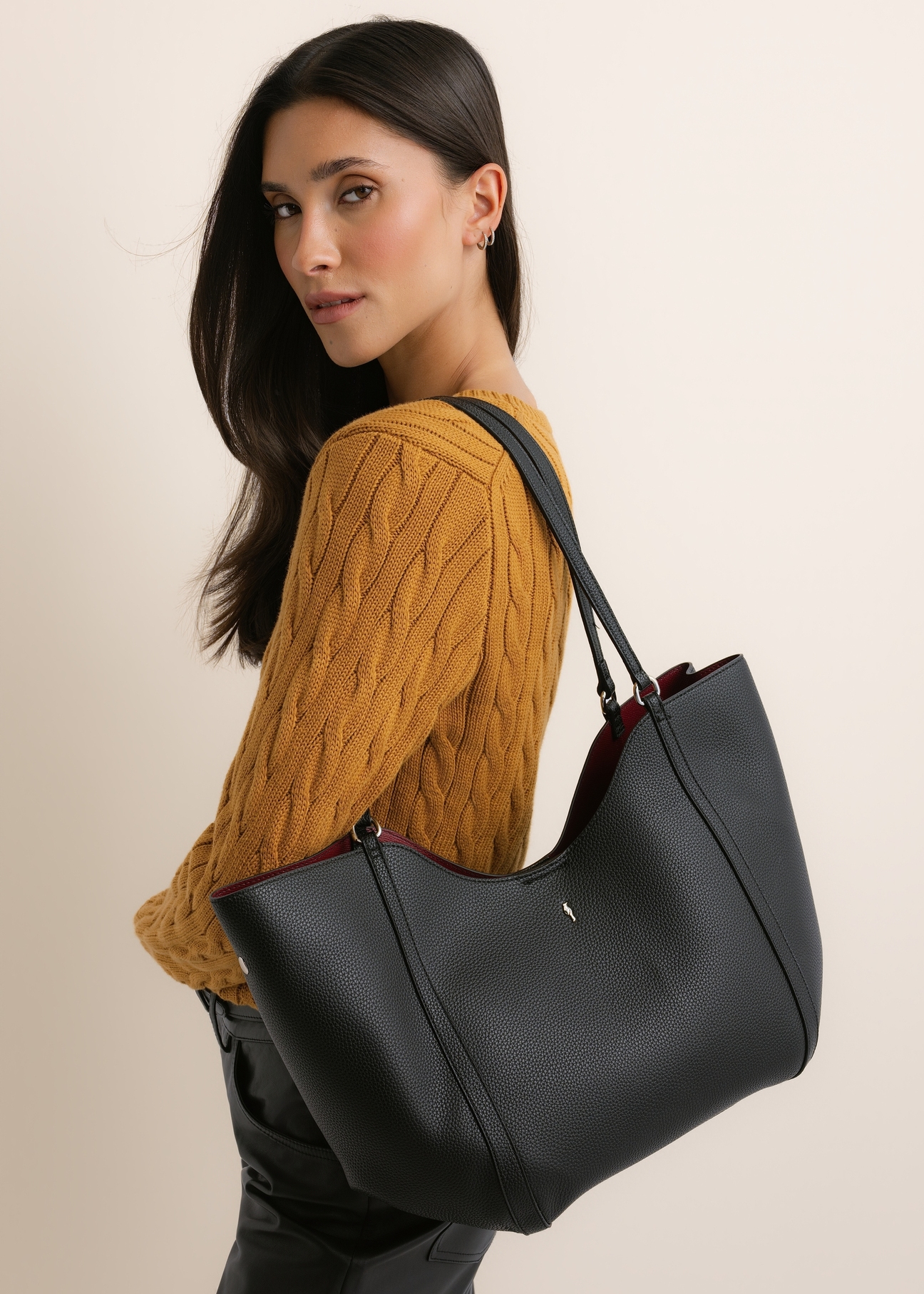 Black women's shopper bag TOREC-1296-9I(Z26), front view of the product, on a model, on a light background. Half silhouette visible.