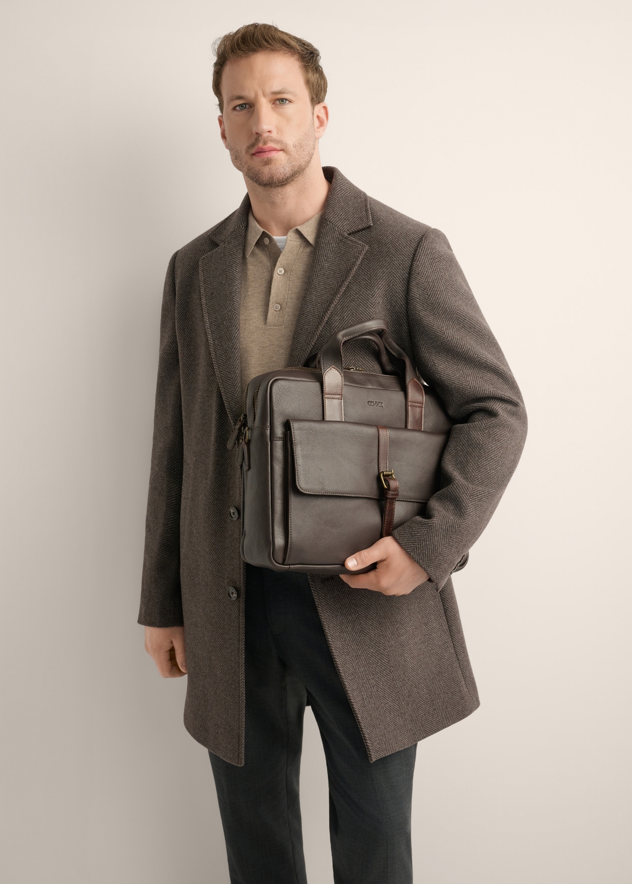 Brown leather men's laptop bag TORMS-0522-1H(Z26), diagonal view of the product in the model's hand, on a light background.