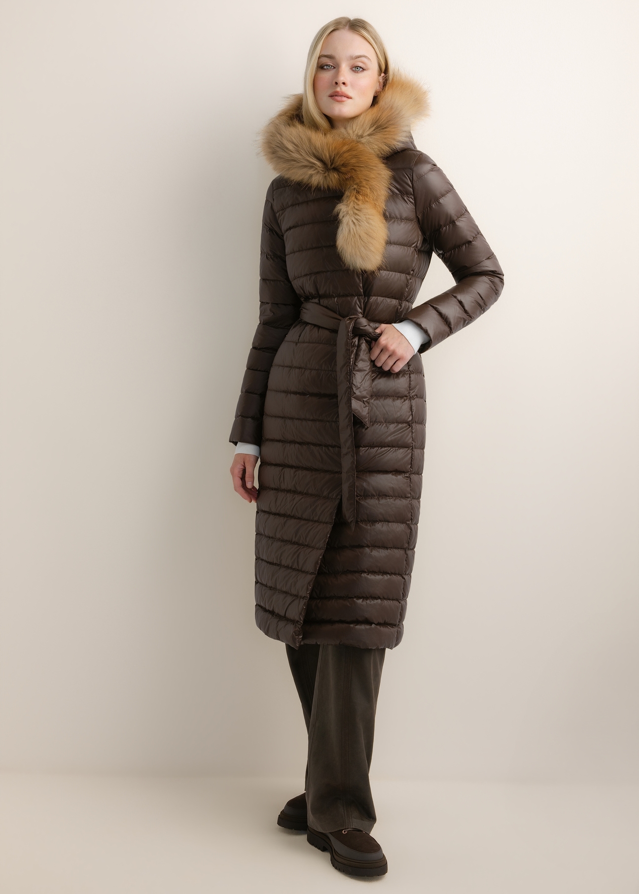 Dark brown long women's jacket with fur KURDT-0706-1I(Z26), front view of the product on the model. Full body visible.