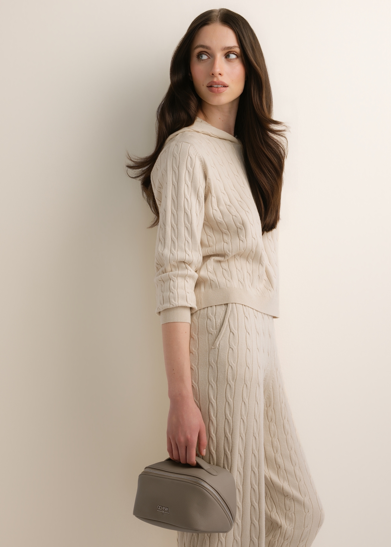 Women's cosmetic bag in cool beige (TOREC-1310-1K(Z26)), shown at an angle on a model; half of the figure is visible.