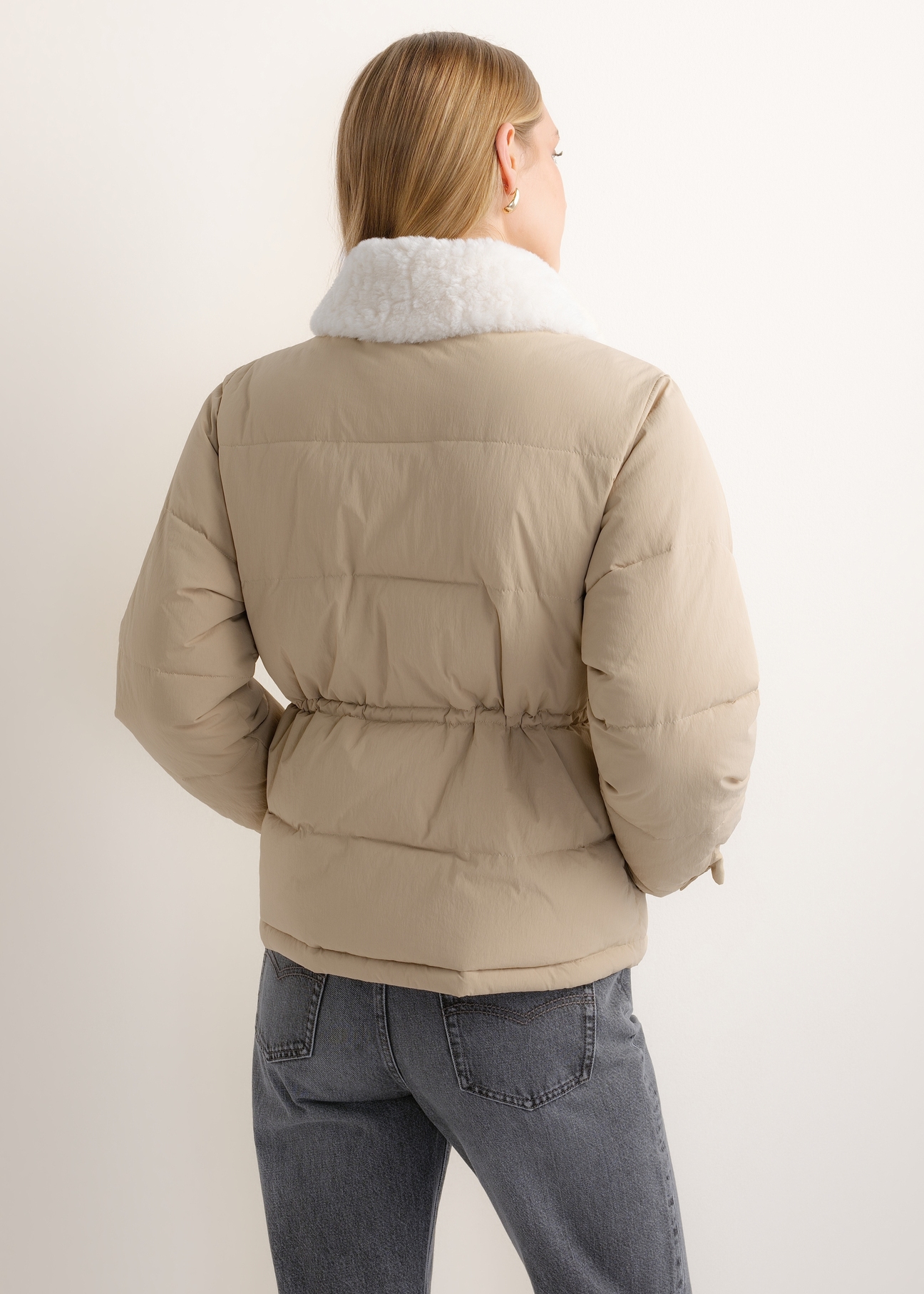 Short beige women's jacket KURDT-0695-1B(Z26), back view of the product on the model. Half of the silhouette visible.