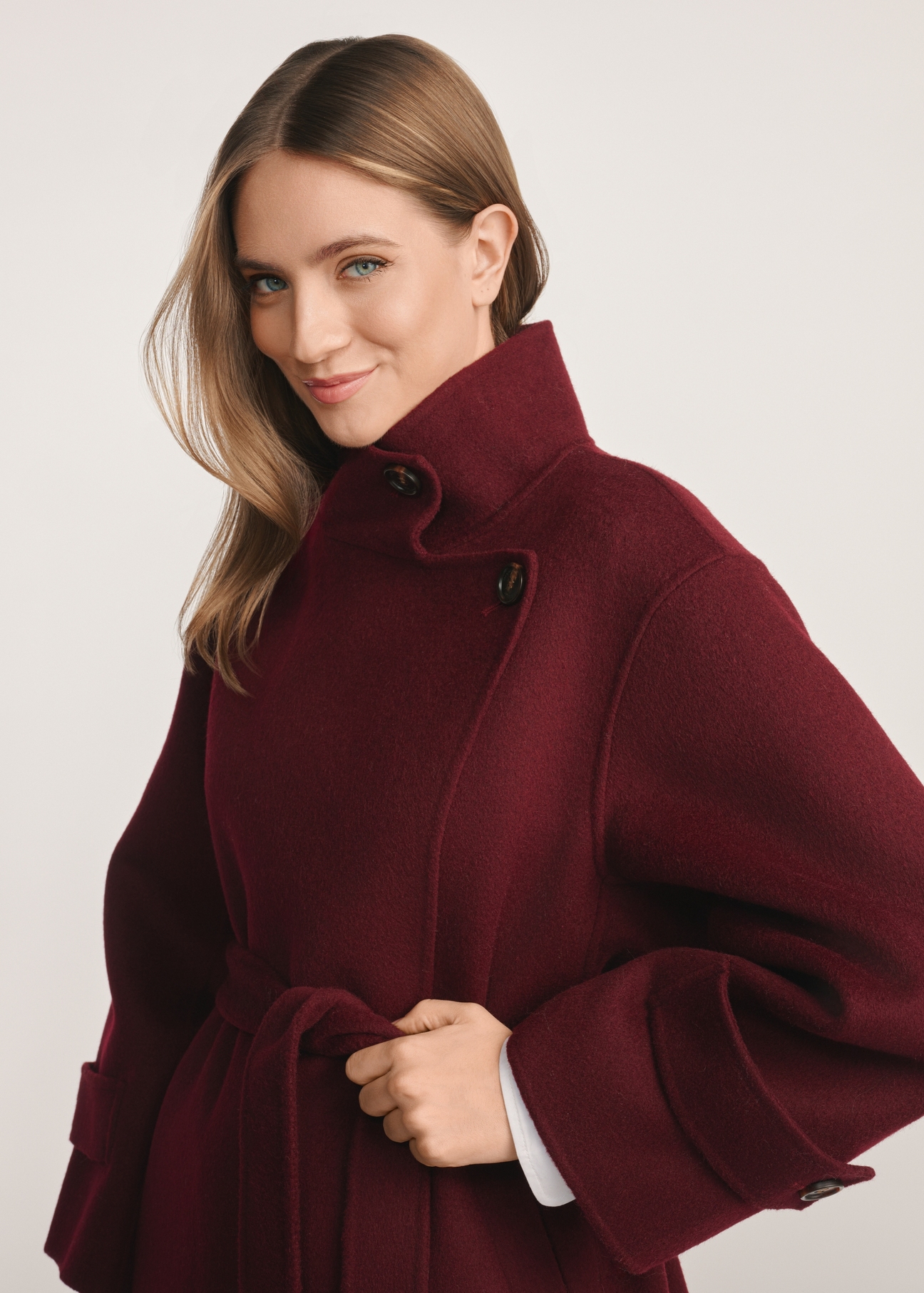 Burgundy women's coat PLADT-0068-49(Z25), product visible from the side on the model, half of the silhouette visible.