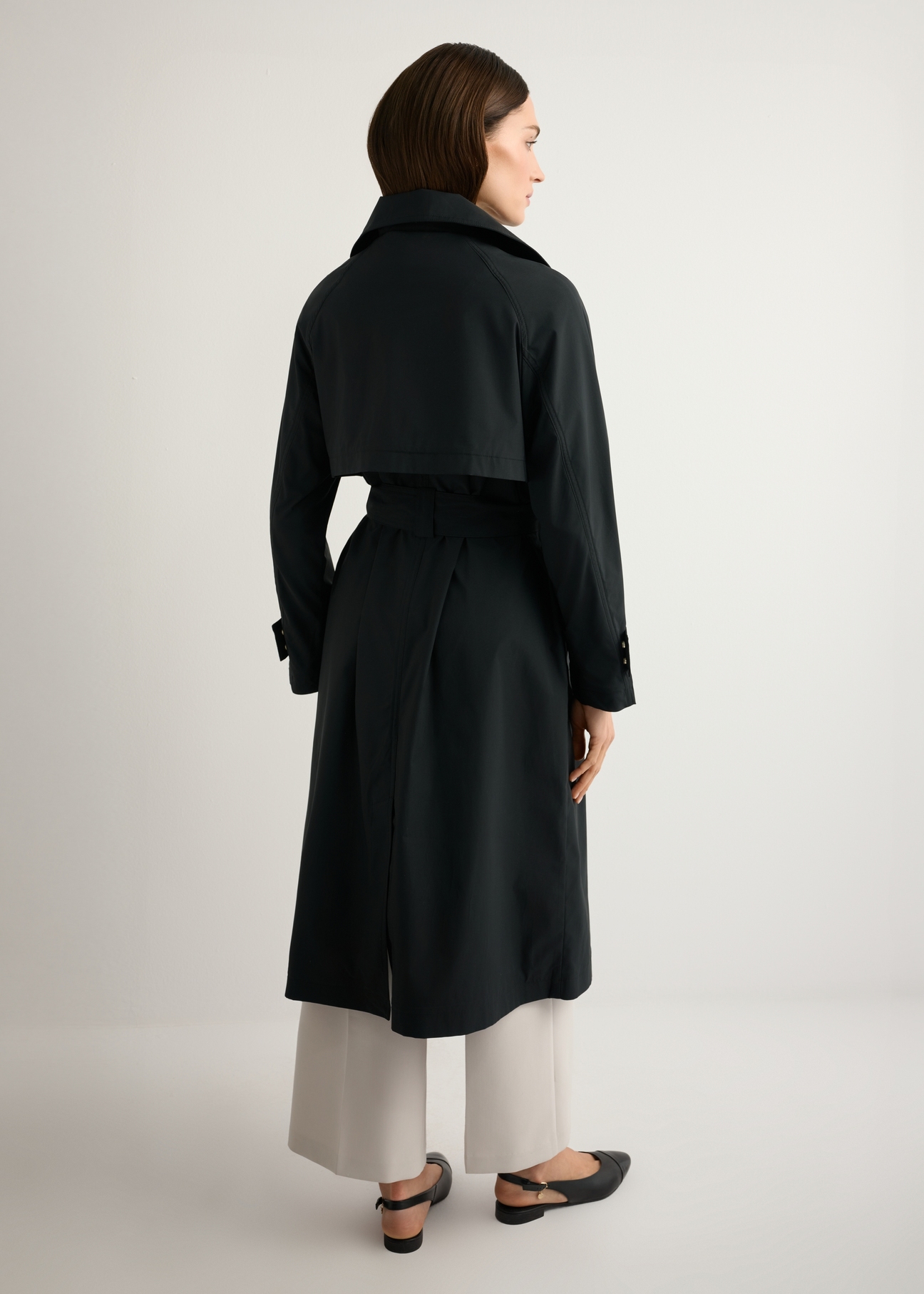Women's black long coat KURDT-0653-99(W26), product view from the back on the model. Full body visible.