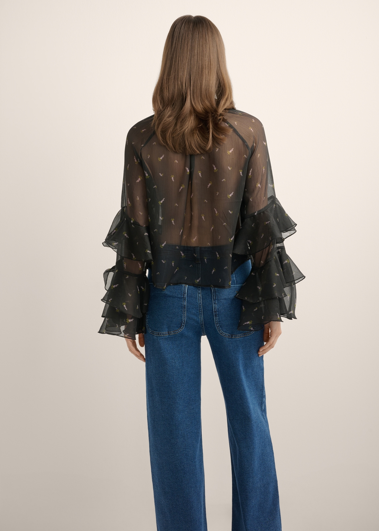 Women's black blouse with a lilac pattern BLUDT-0212-9P(Z26), product view from the back on the model. Half of the silhouette visible.