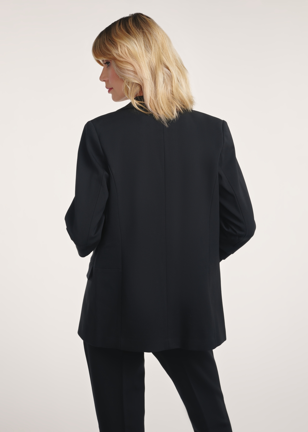 Black women's blazer without fastening ZAKDT-0034-99(Z24) - product view from the back on a model on a white background. Half of the silhouette visible.