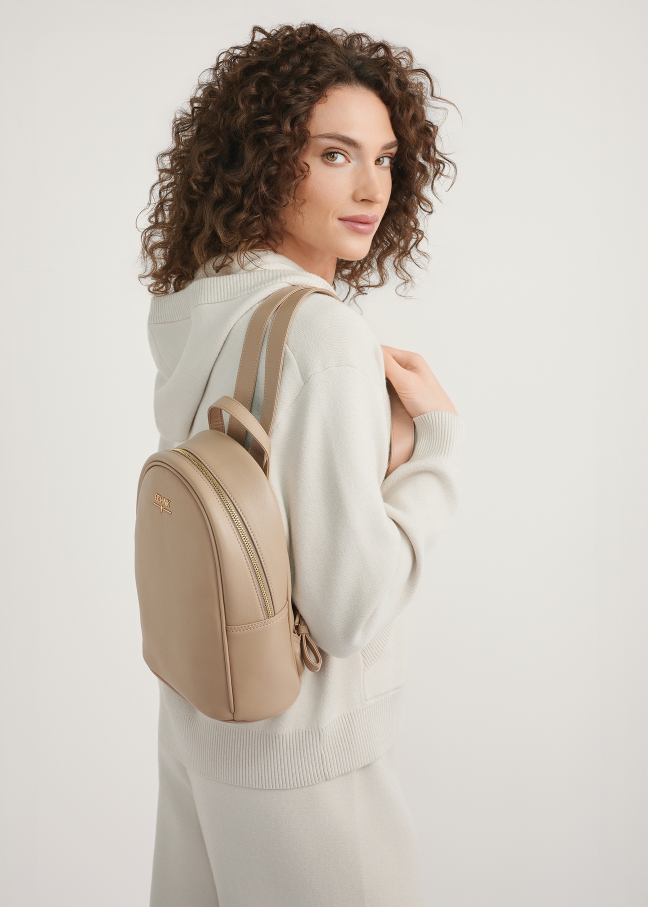 Beige leather women's backpack TORES-1228-1B(W26) - product view on a model against a light background. Half of the silhouette visible.