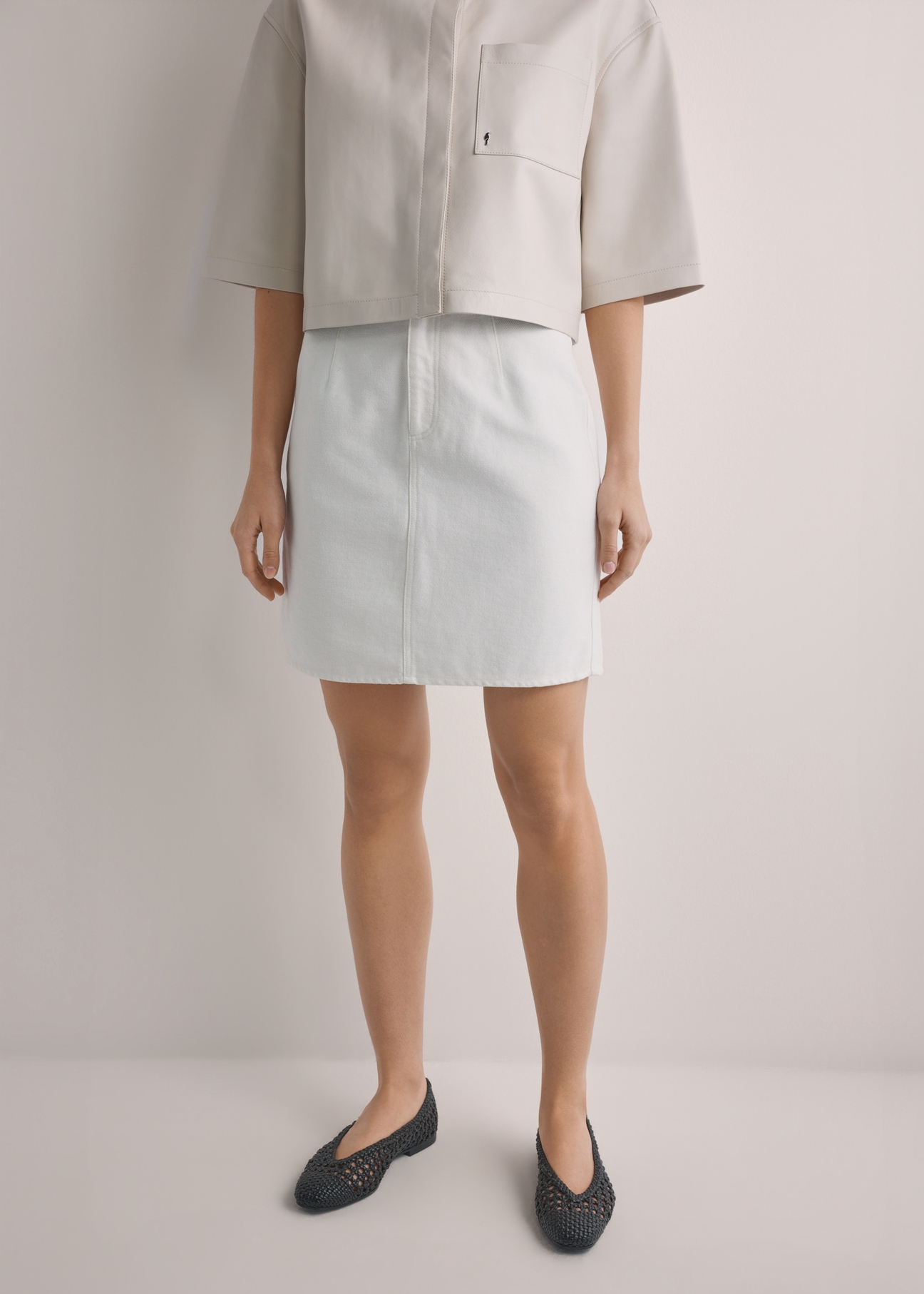 Cream denim mini skirt SPCDT-0126-0B(W26), front view of the product on the model. Half of the silhouette visible.