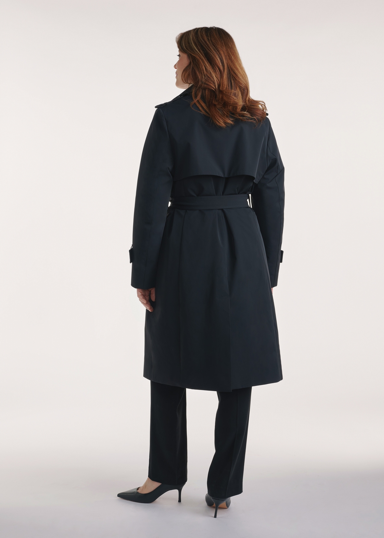 Black women's coat with insulation KURDT-0610-99(Z25), product view from the back on the model, the whole silhouette is visible.