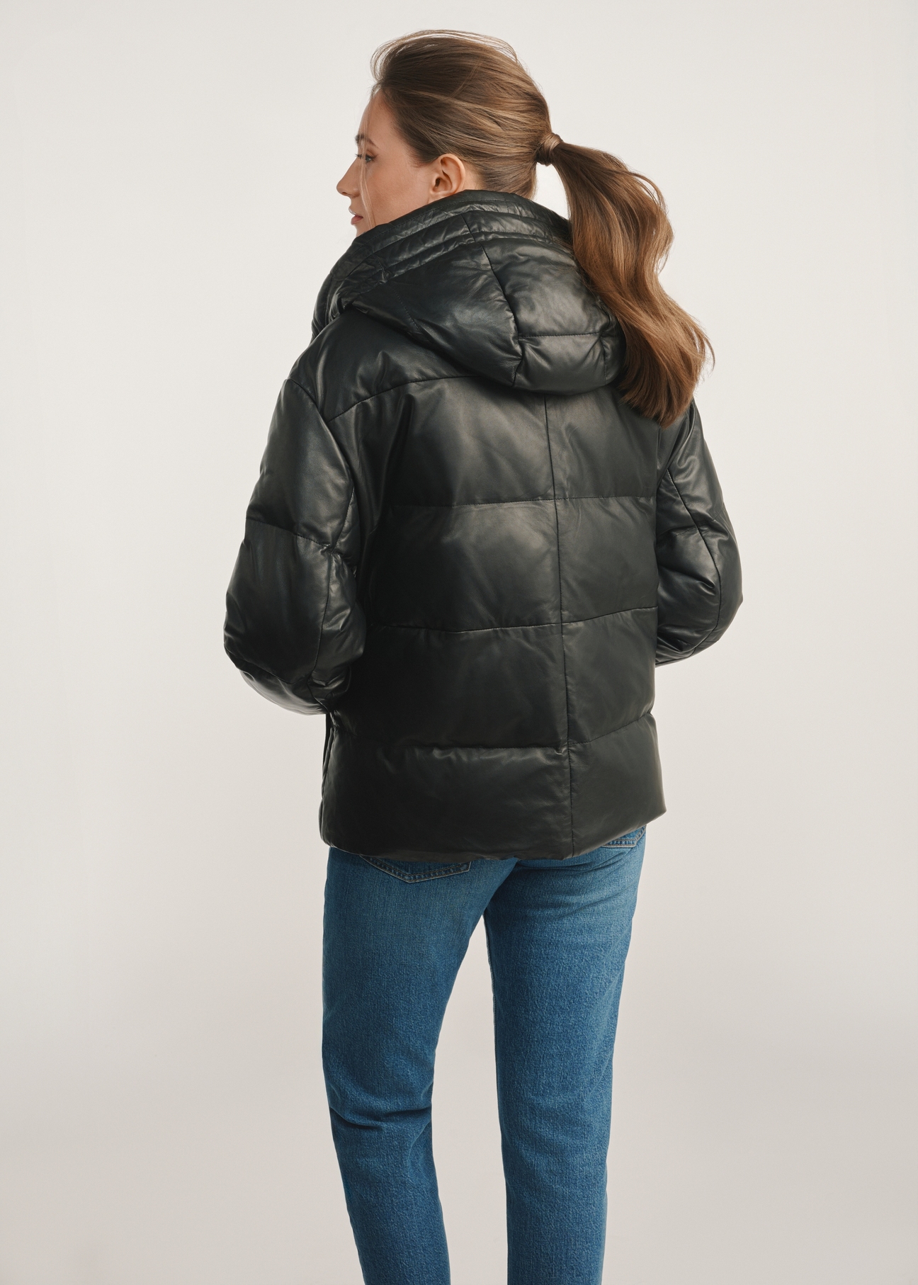 Women's black insulated leather jacket KURDS-0561-5344(Z25) - back view of the product on a model against a white background. Knee-length silhouette visible.