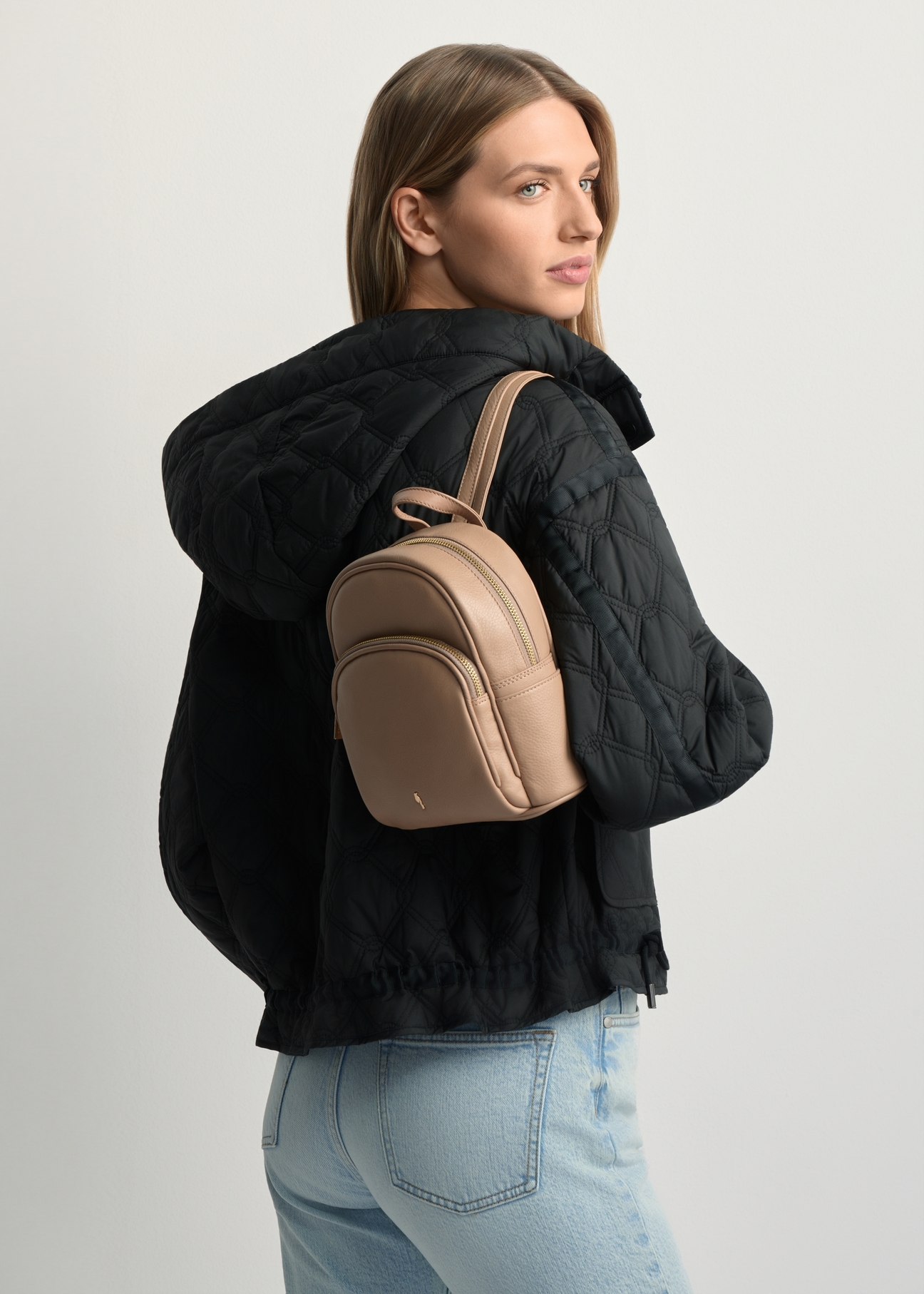 Beige leather women's backpack TORES-1089A-1B(W26) - diagonal view of the product, on a model against a light background. Half of the silhouette visible.